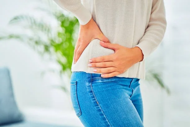 A person holding their lower back and side hip, representing femoroacetabular impingement (FAI) and hip pain treatment at Indy Spine and Rehab in Carmel, Indiana.