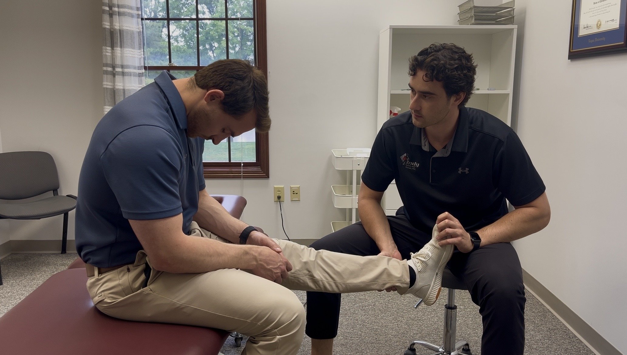 Sports chiropractor Dr. Owen Friest performing a clinical slump test to evaluate sciatic nerve tension and disc irritation at Indy Spine and Rehab.