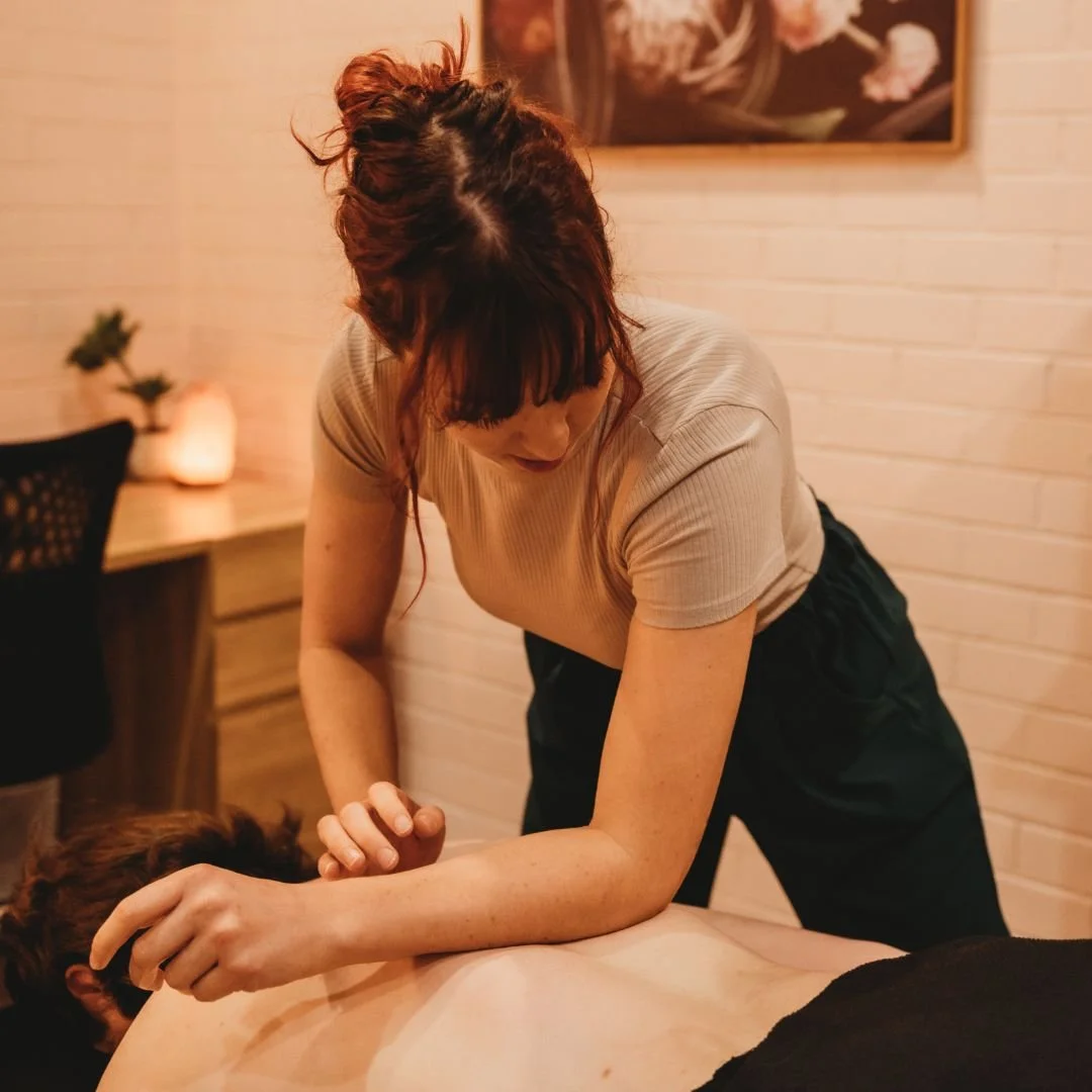Therapist massaging patients back and shoulders in warm clinical setting