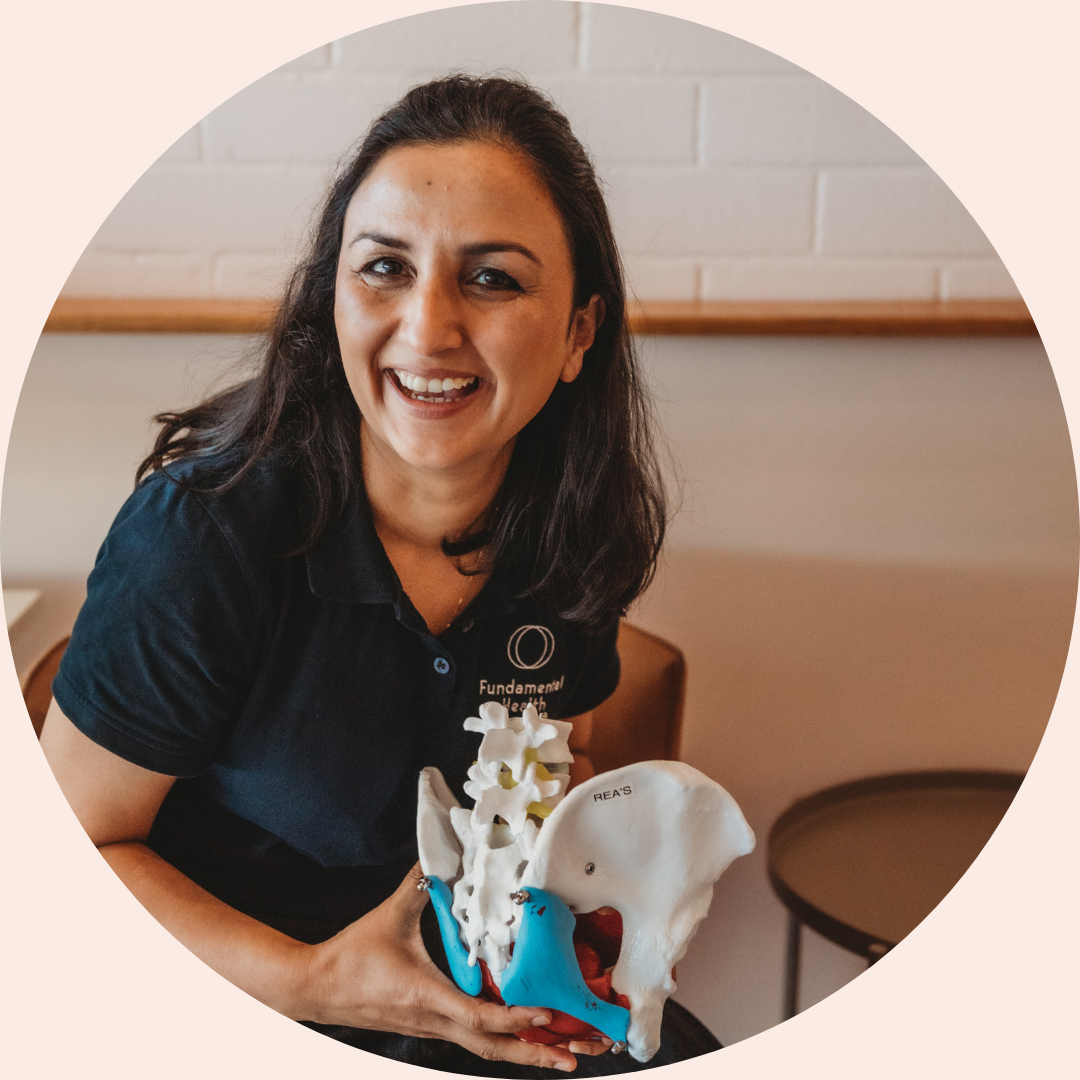 Gurpreet holding a model pelvis and smiling at camera