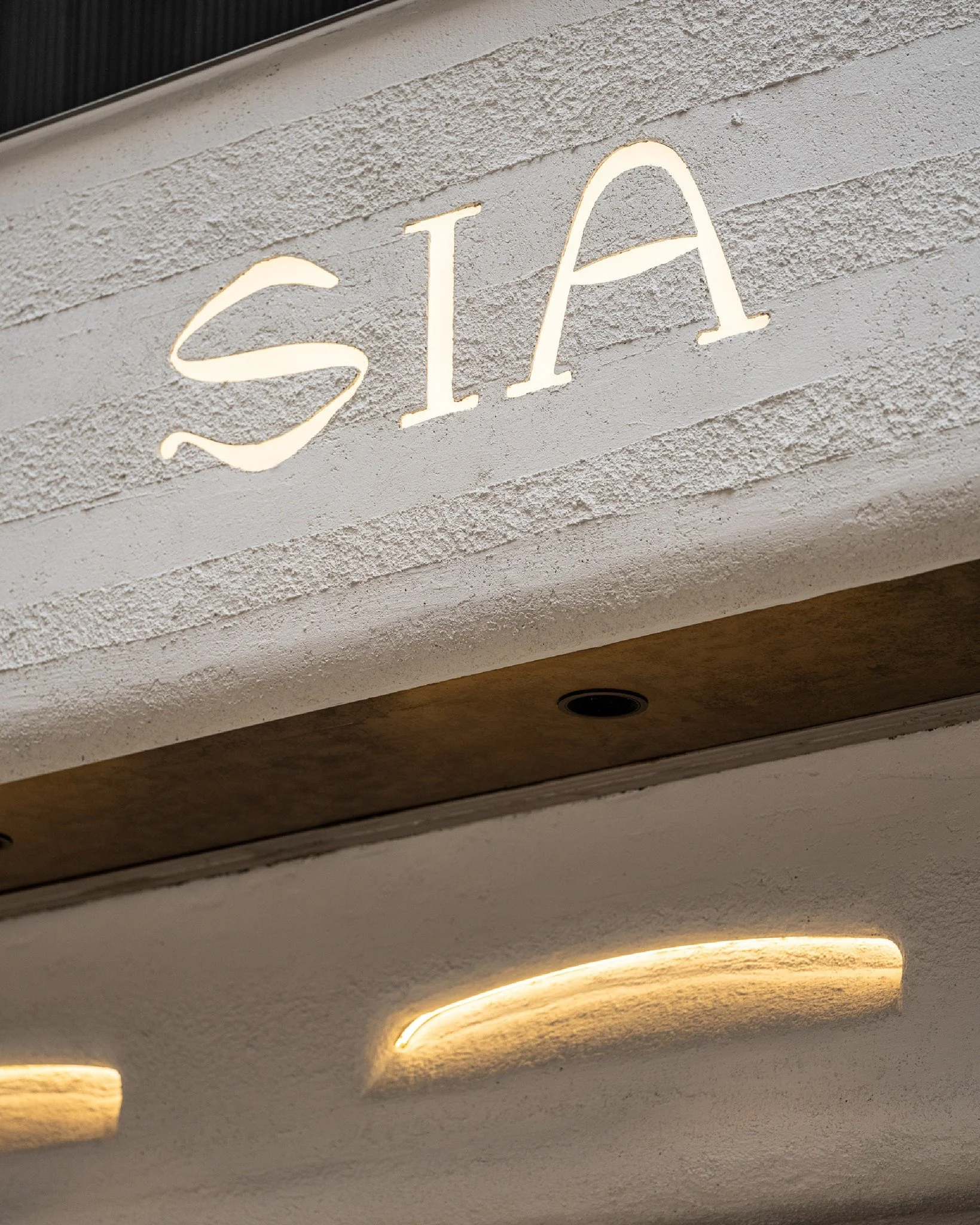 The space embodies a natural vault safeguarding precious treasures. The journey begins at the facade, where textured surfaces resemble raw cave walls. The water droplet-like bespoke lighting by the entrance offers a secretive invitation to enter the 