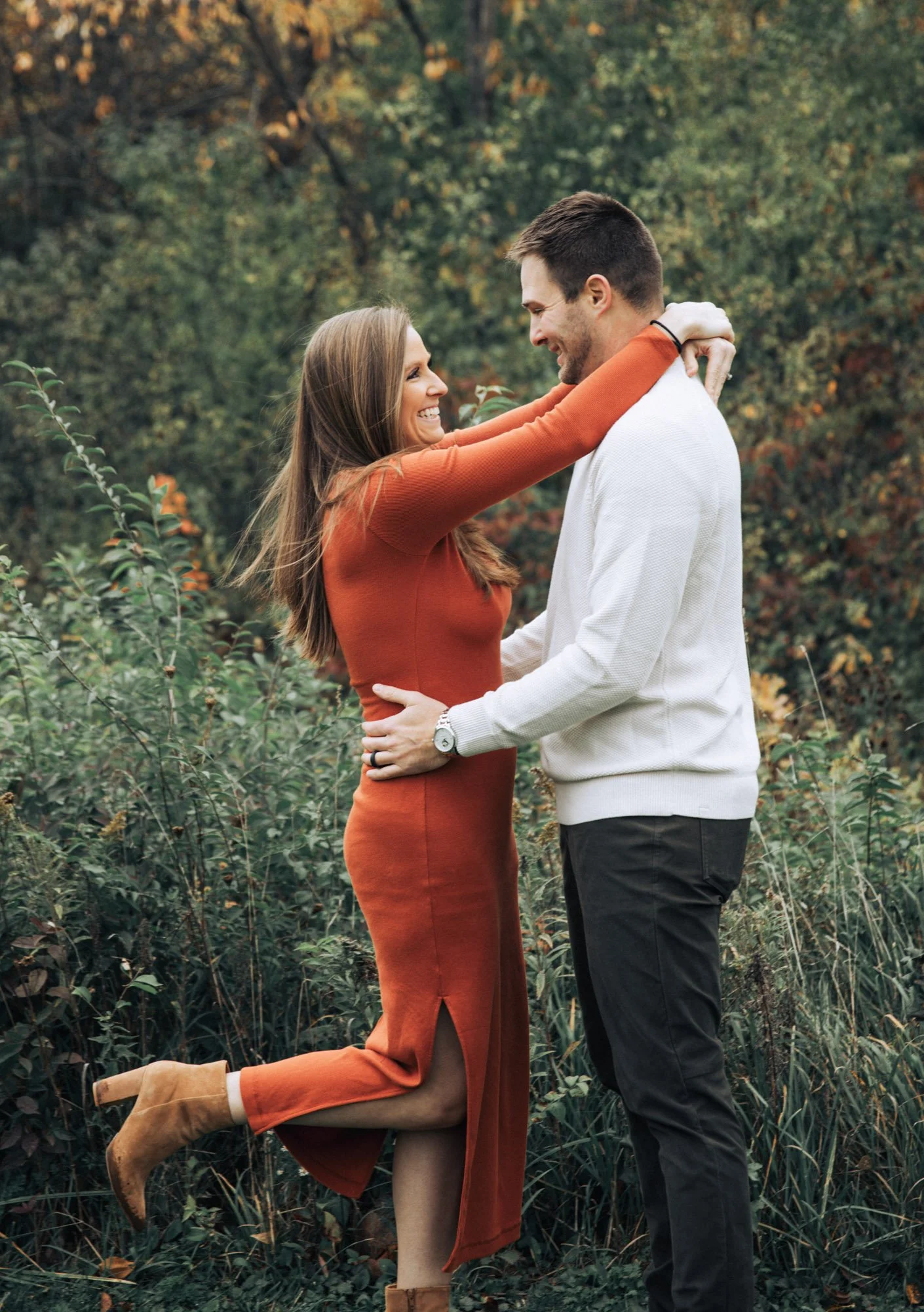 Canton Michigan engagement photography of A couple embracing outdoors in a wooded area, smiling and happy.