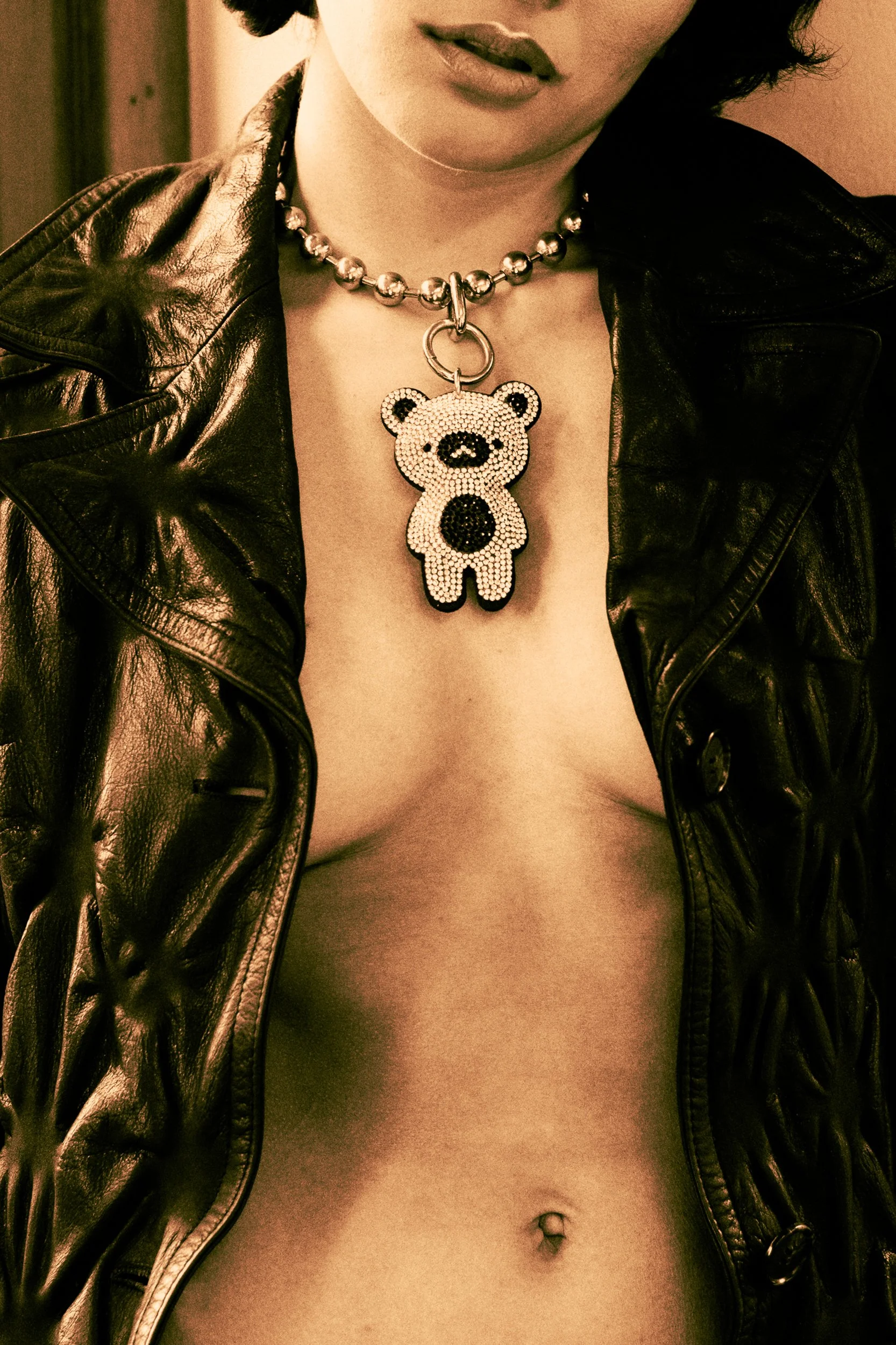 A woman wearing a leather jacket and a necklace with a bear-shaped pendant covered in rhinestones, photographed during a fashion editorial photography session in Los Angeles with fashion photographer Gí Tenamá..