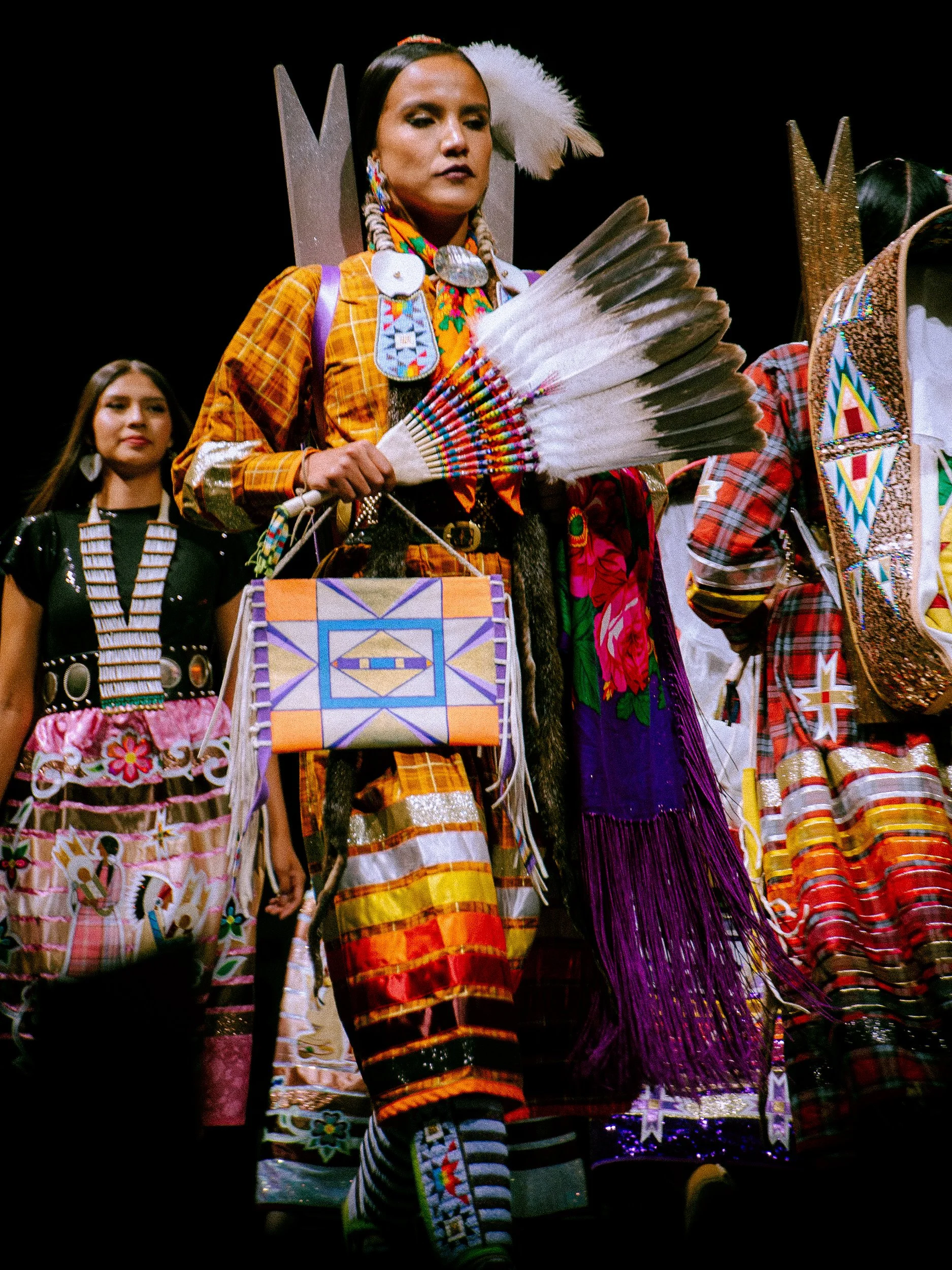 Women dressed in colorful traditional Native American clothing, participating in a cultural event or parade.