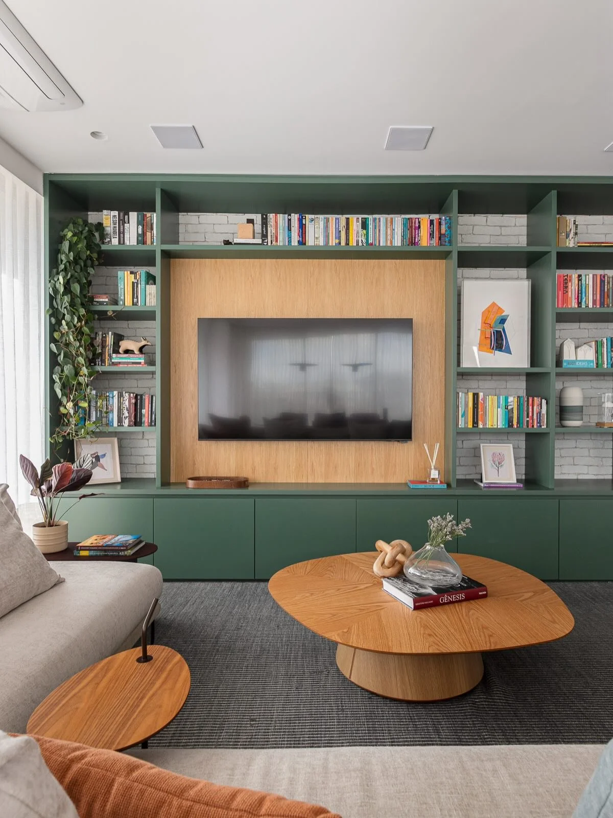 DS Ap Vila Madalena JG &bull; Uma estante verde com fundo de tijolinhos r&uacute;sticos 💚 &bull; ela abra&ccedil;a a TV, a vitrola, os livros e muitos objetos lindos dos clientes! Amamos essas estantes que contam hist&oacute;rias e fazem a gente ide