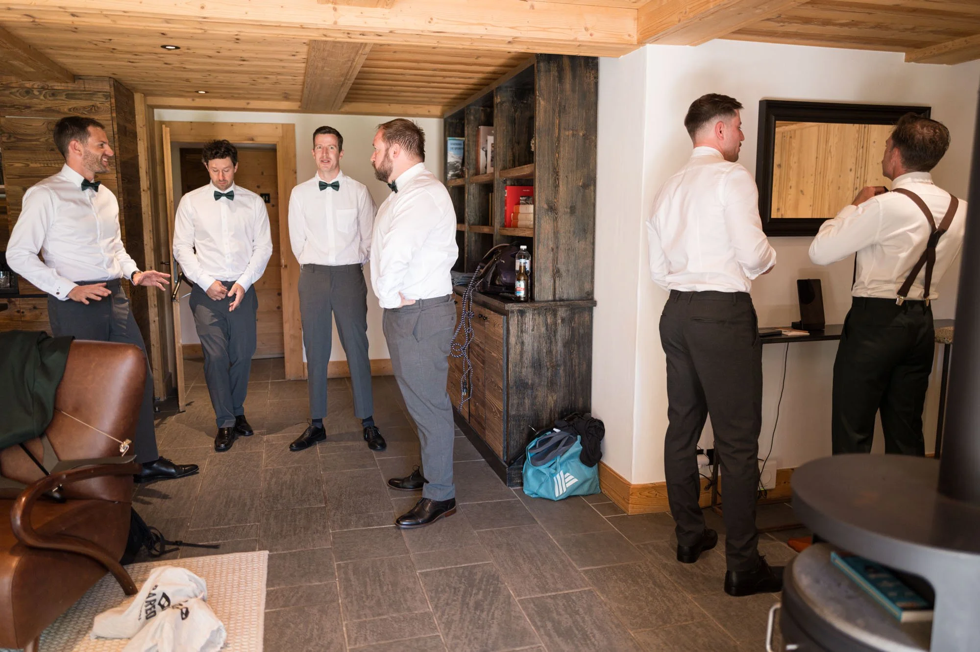 Groupe de sept hommes en costume formel discutant dans une pièce avec un décor en bois et rangement.