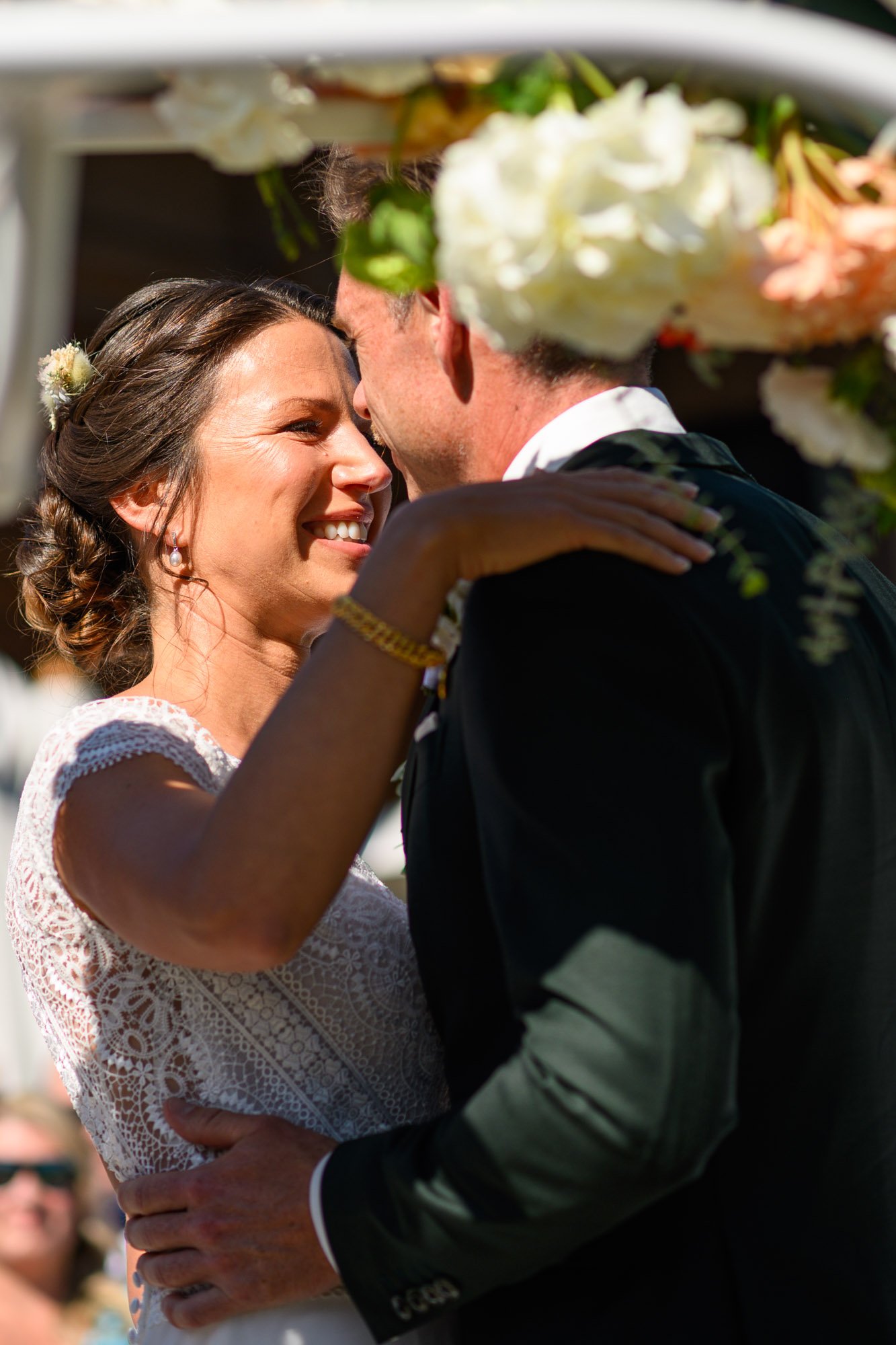 Un couple danse lors de leur mariage, souriant et regardant dans les yeux, sous un décor floral en extérieur.