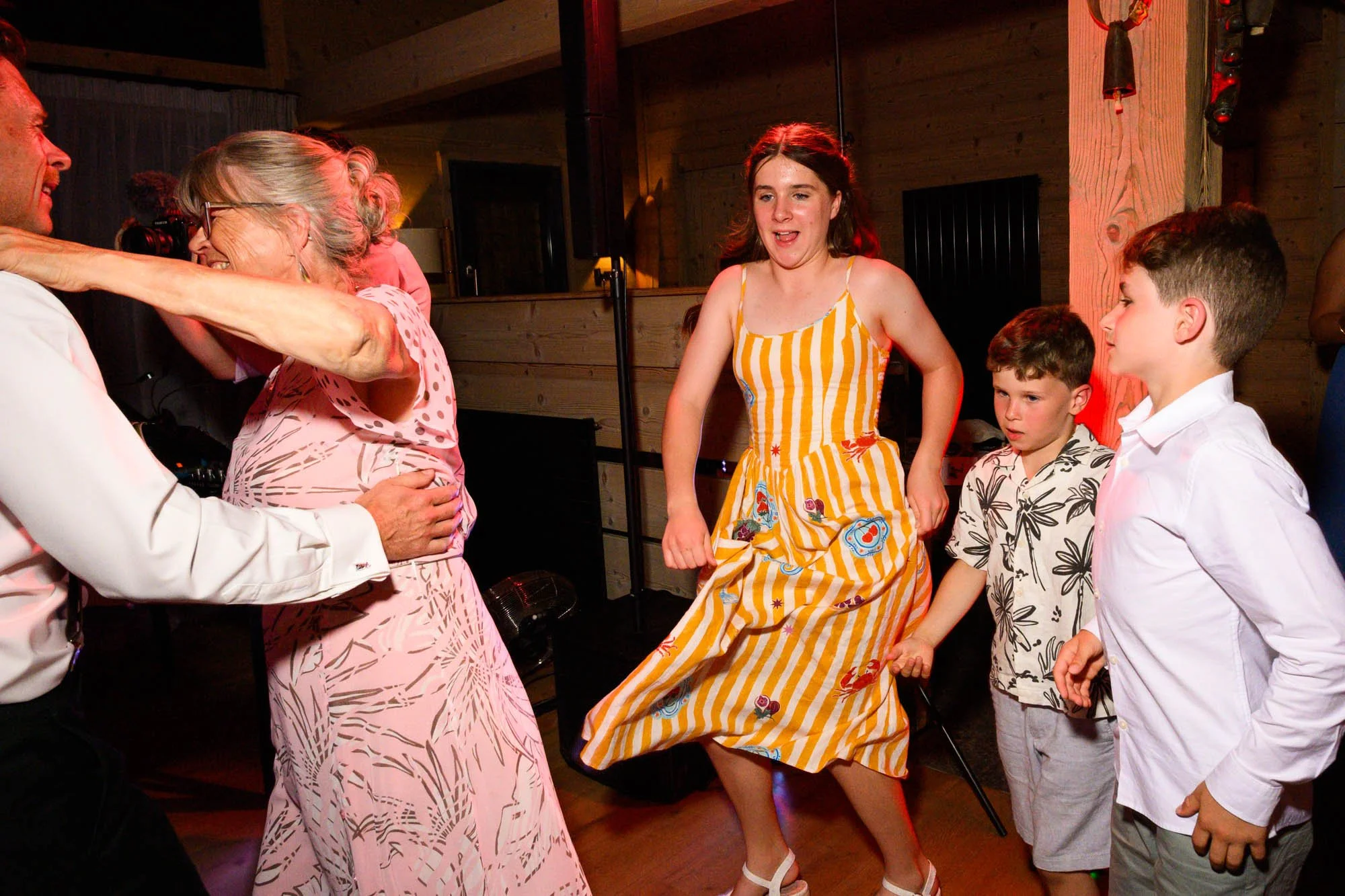 Groupe de personnes qui dansent et s'amusent lors d'une fête dans un environnement intérieur en bois.