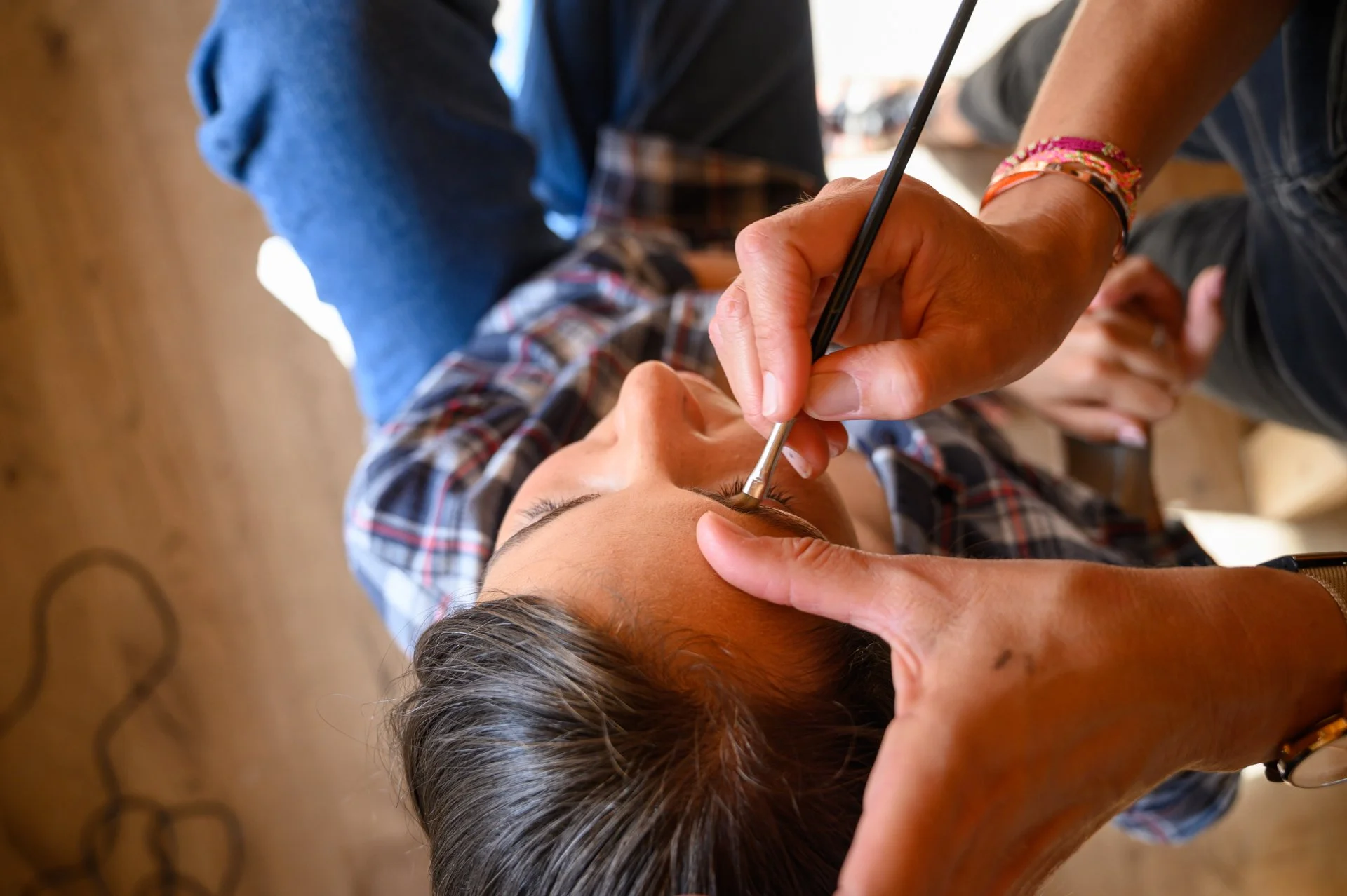 Une femme reçoit un maquillage ou un soin du visage avec un pinceau par une autre personne.
