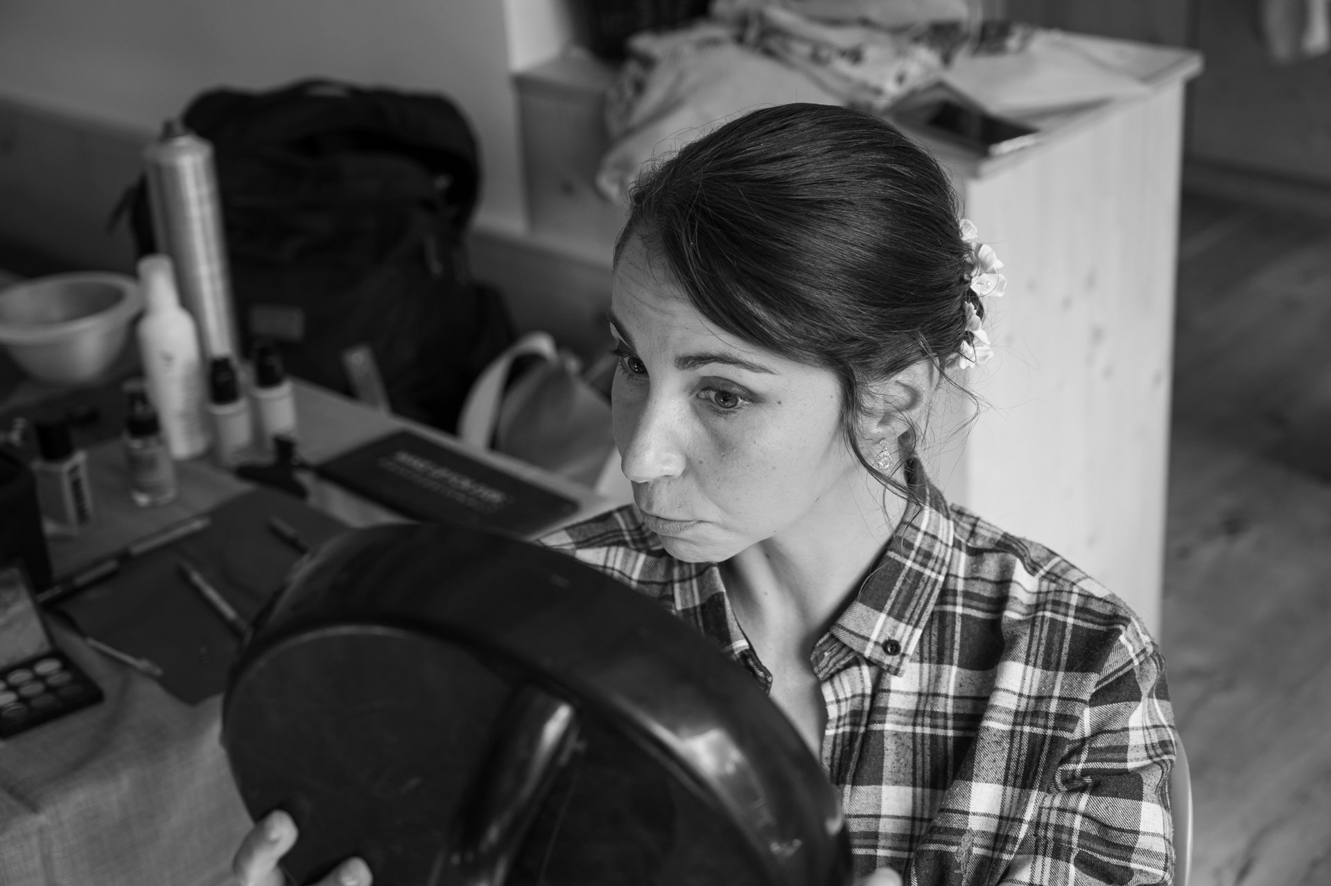 Une femme se maquille en utilisant un miroir, entourée de divers produits cosmétiques sur la table