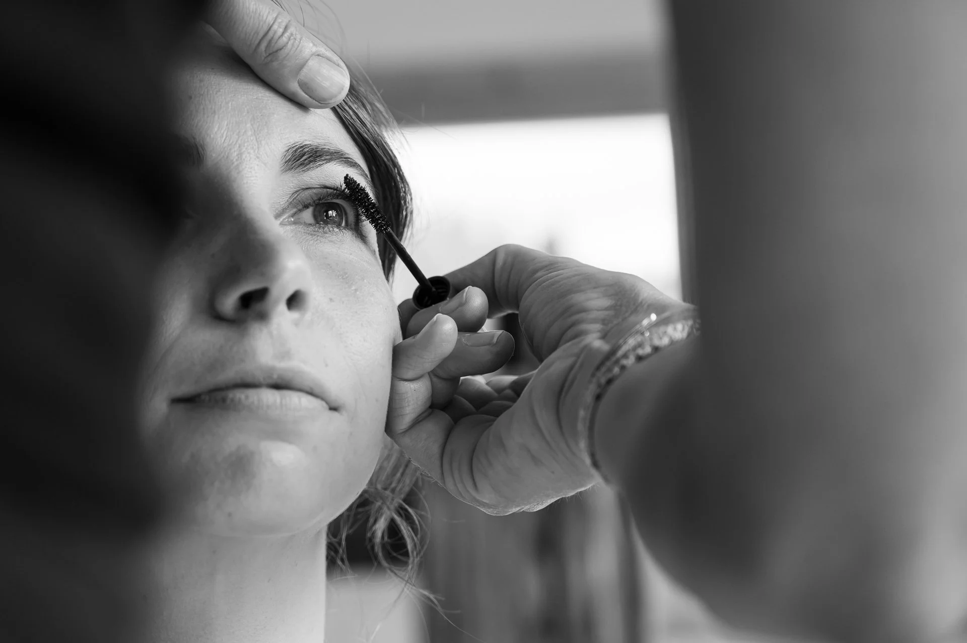 Une femme reçoit une application de mascara sur la ligne des cils lors d'une séance de maquillage.