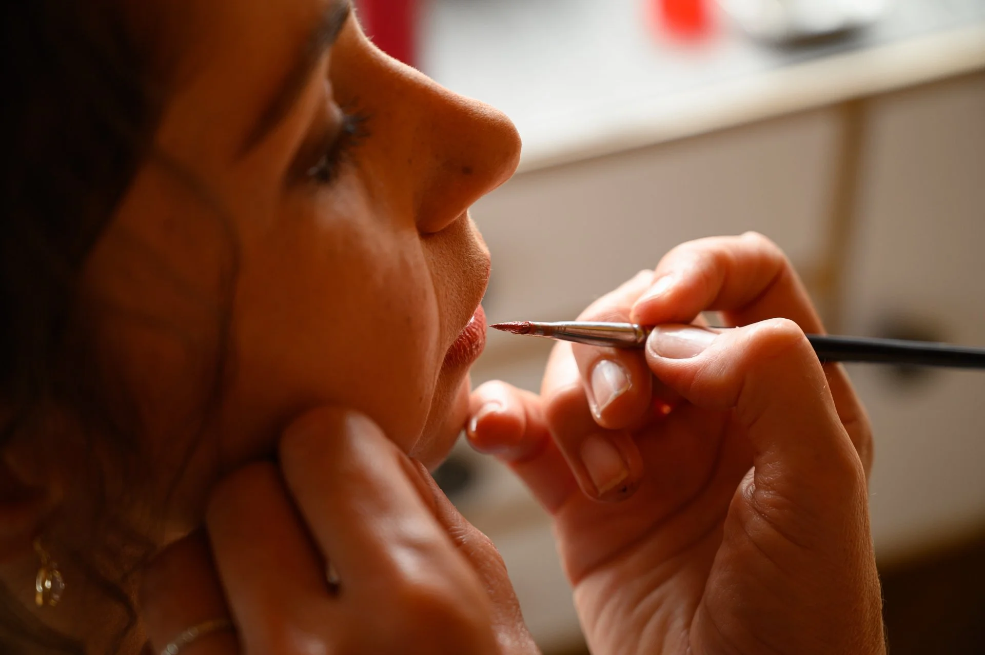 Une femme se fait maquiller les lèvres avec un pinceau par un professionnel.