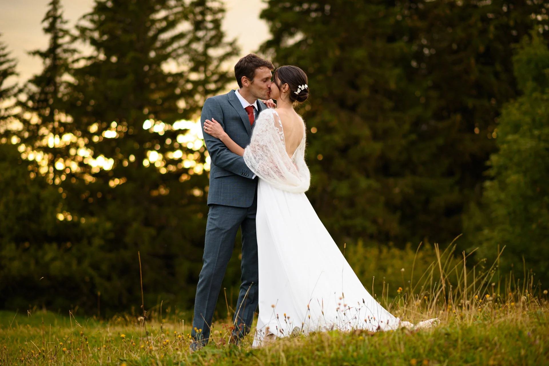 Un couple de mariés s'embrassant dans un champ lors d'un coucher de soleil.