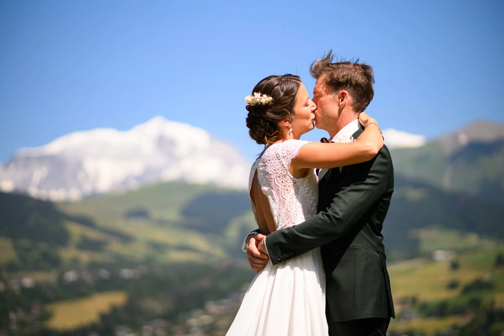 Un couple de mariés s'embrassant avec un paysage de montagnes en arrière-plan.