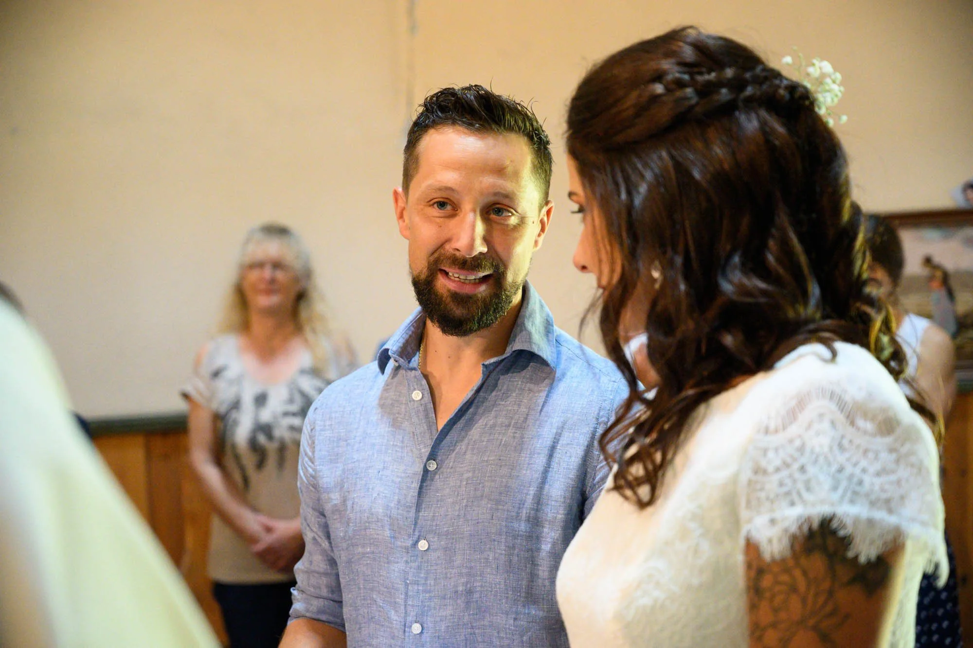 Un homme et une femme discutent lors d'une cérémonie, avec d'autres personnes en arrière-plan.