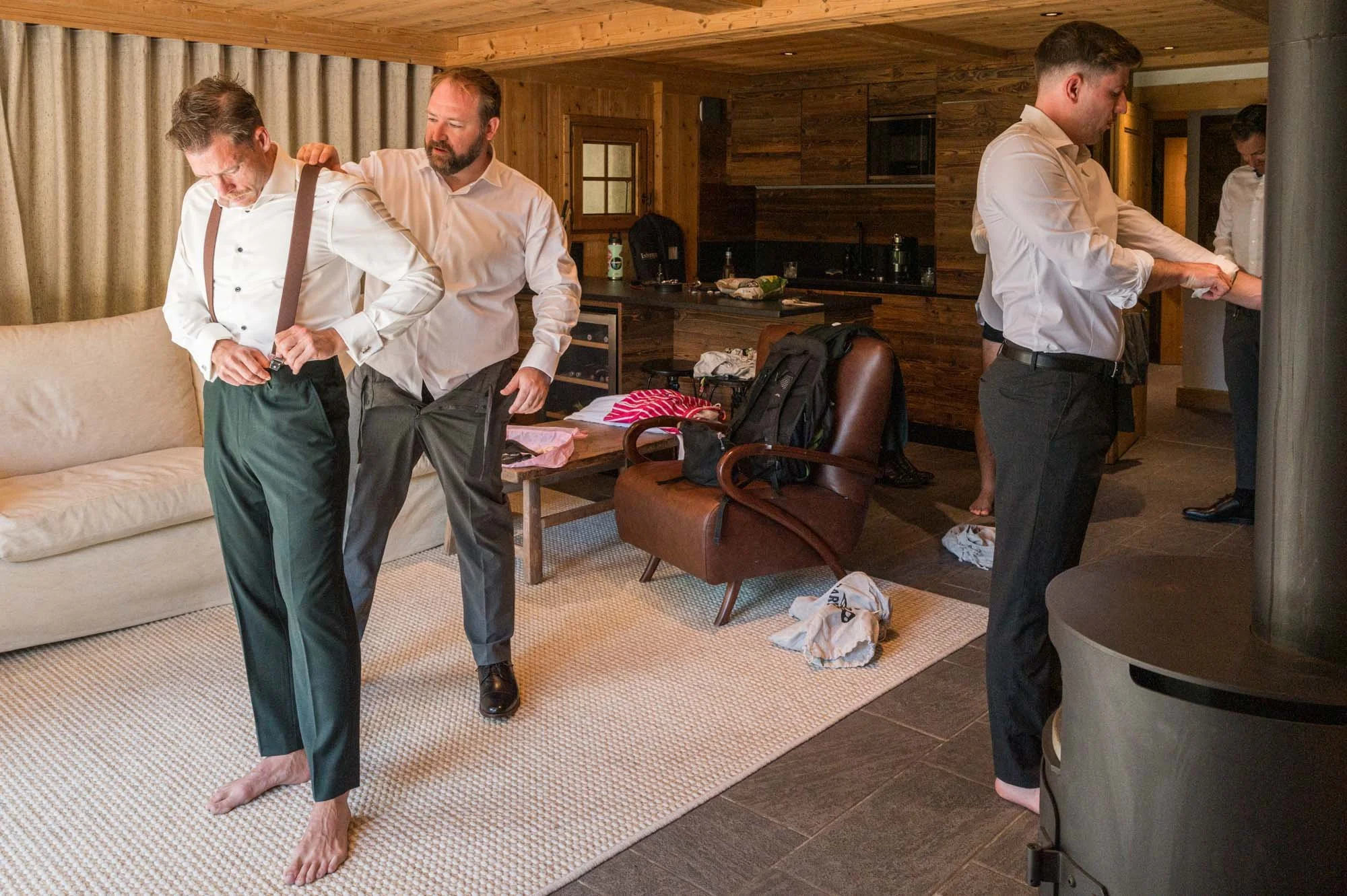 Homme aidant un autre homme à se mettre en pantalon dans un salon boisé