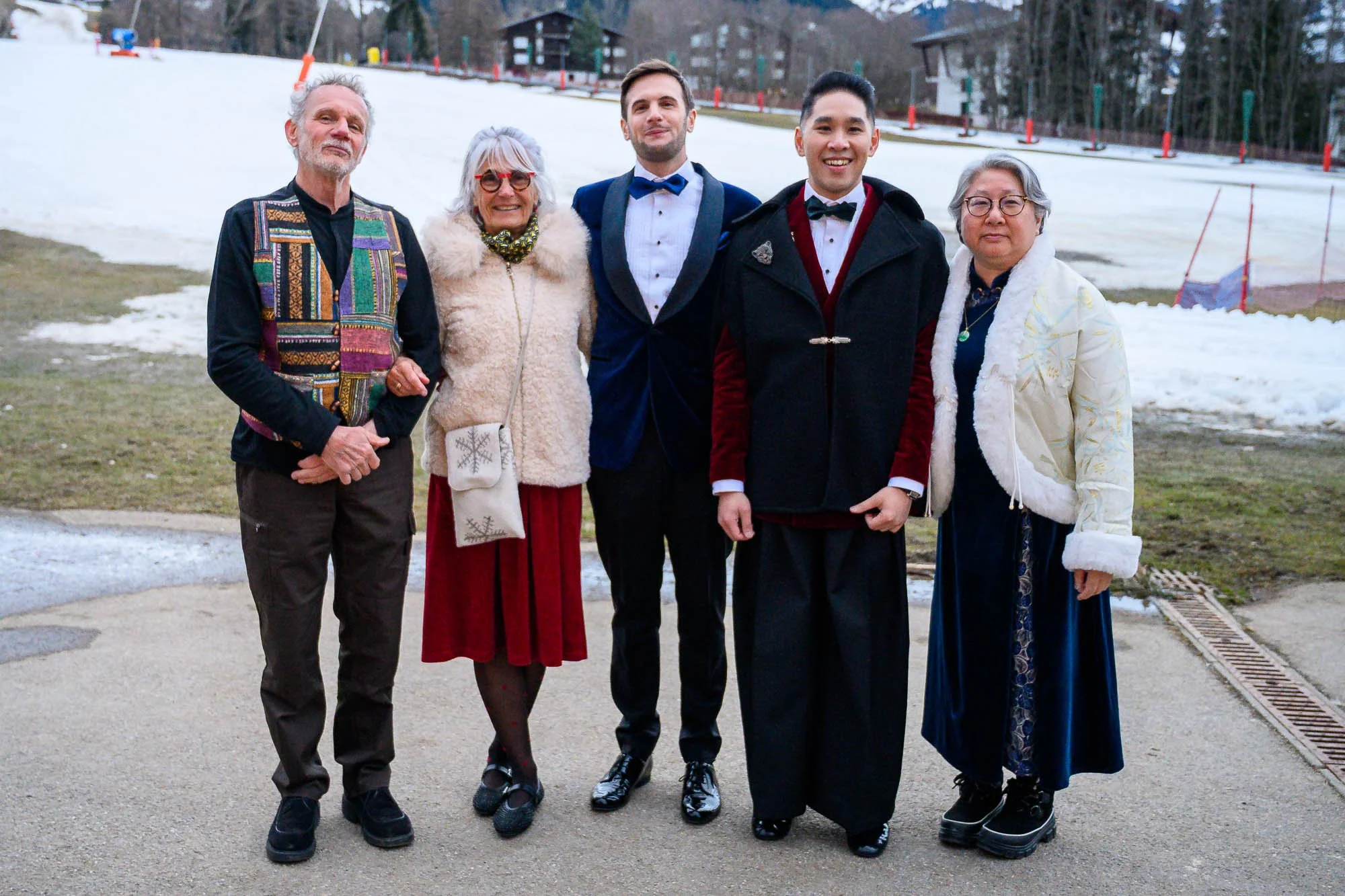 Groupe de six personnes posant à côté d'une pente enneigée en hiver.