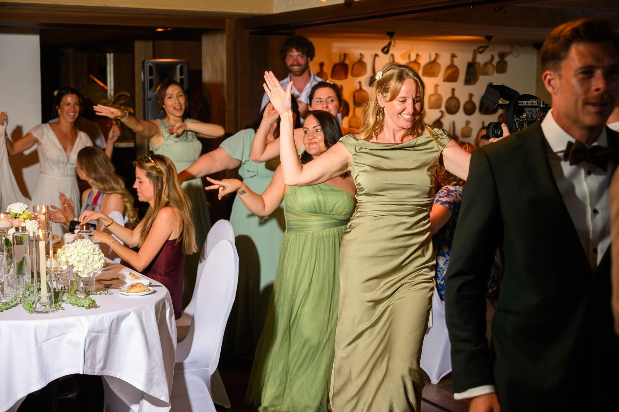 Groupe de personnes dansant lors d'une célébration ou d'une fête, avec décorations et table dressée.