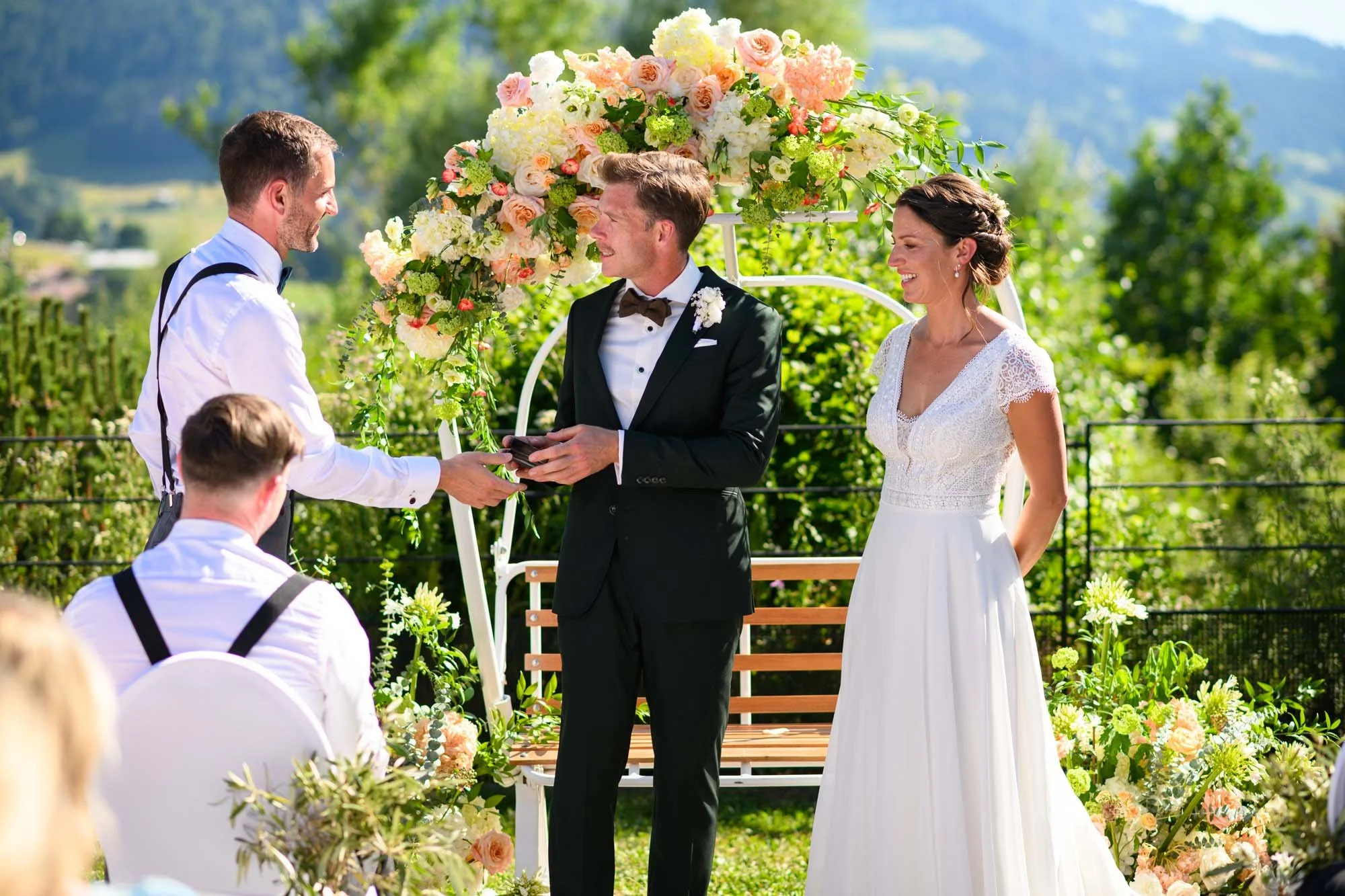 Un couple marié célébrant leur mariage en extérieur, entouré de fleurs et de verdure, lors d'une cérémonie en plein air.