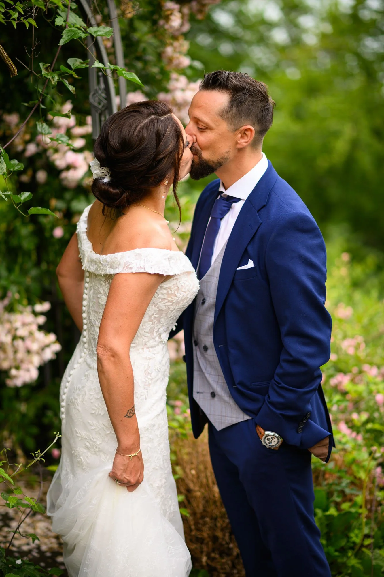 Un couple de mariés s'embrassant dans un jardin lors d'un mariage.