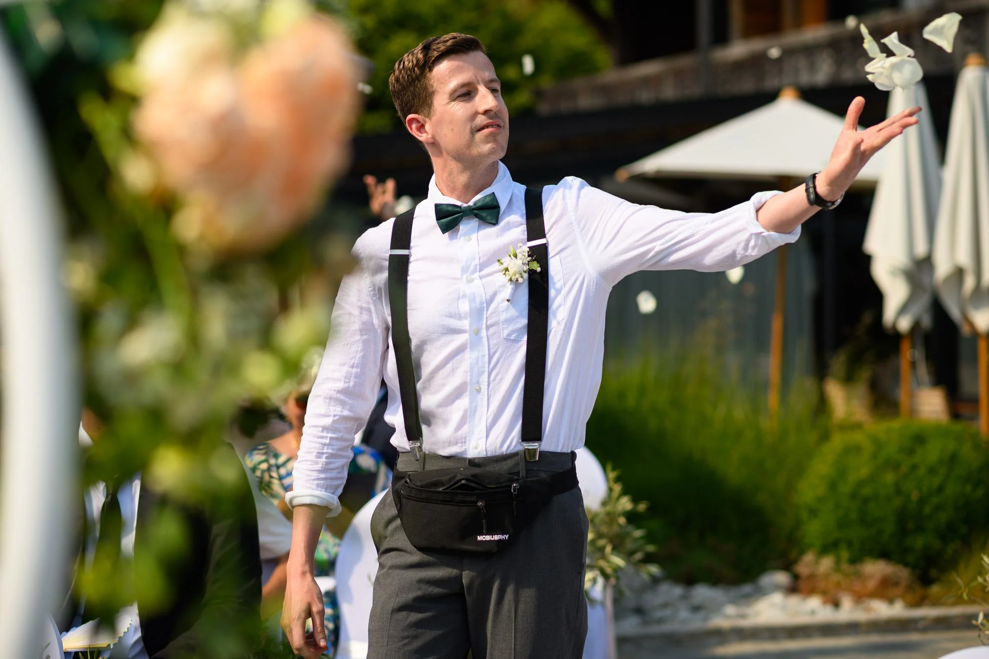 Un homme habillé en style vintage avec une chemise blanche, une cravate et des bretelles, qui donne un ordre ou une direction lors d'un événement extérieur.