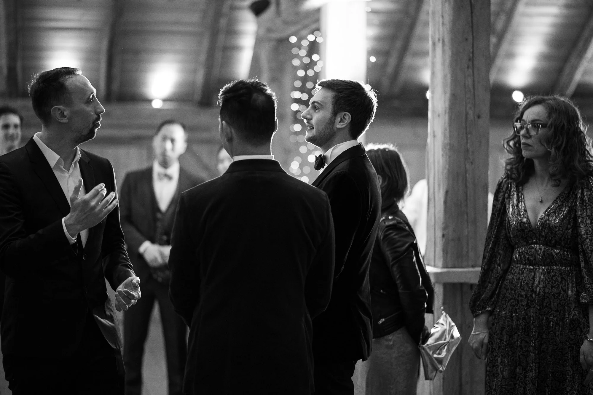 Un groupe de personnes habillées formellement, discutant dans un endroit intérieur avec décorations de fête.