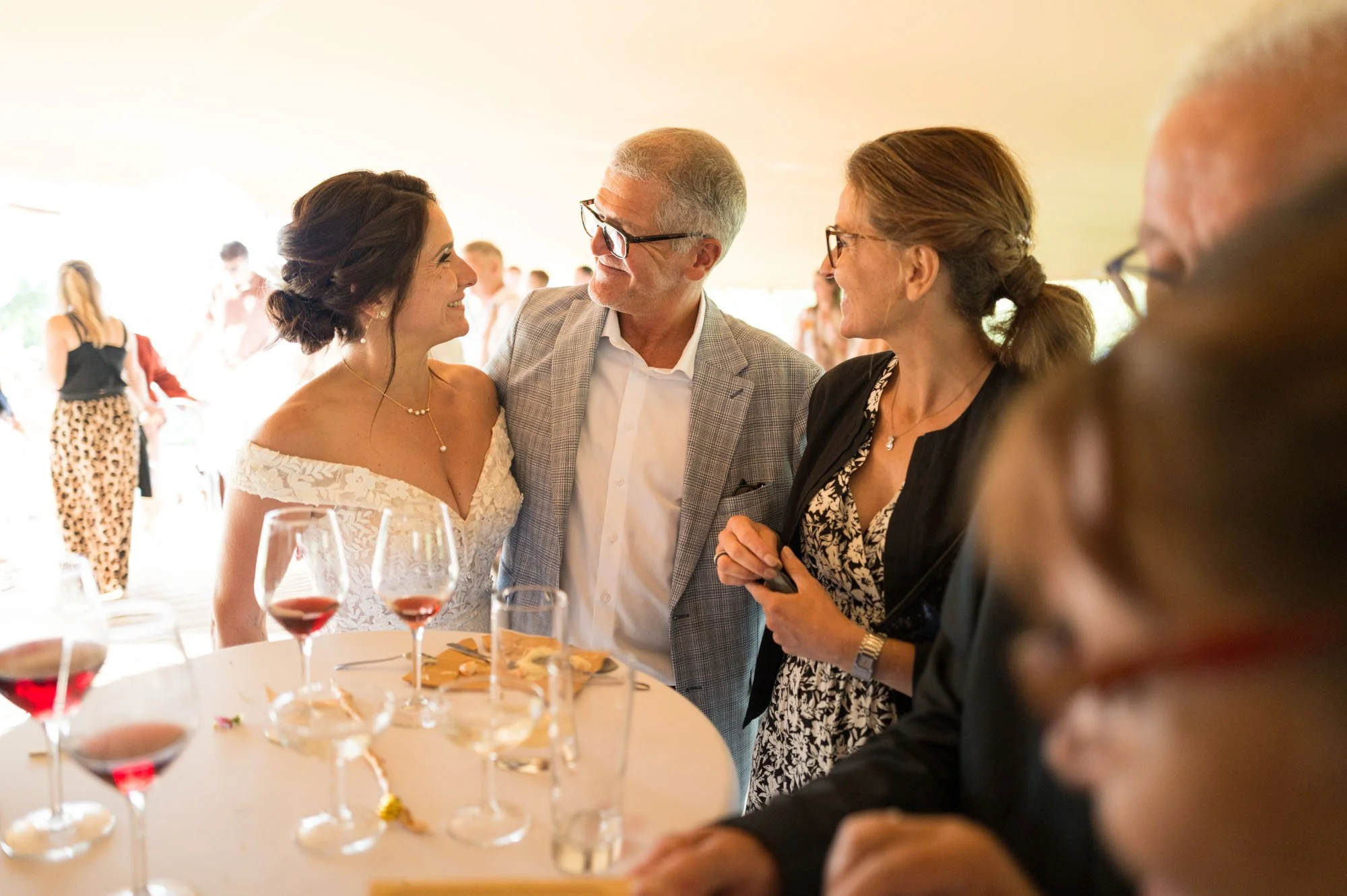 Groupe de personnes en conversation lors d'une fête ou réception, avec verres de vin rouge sur la table, ambiance chaleureuse et conviviale