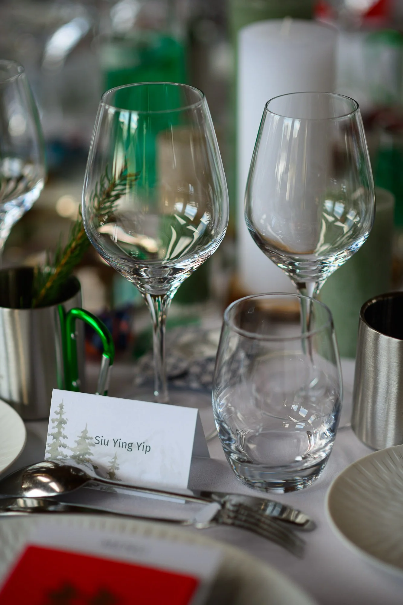 Verres à vin vides et un verre d'eau, sur une table de fête, avec une carte portant le nom "Siu Ying Yip"