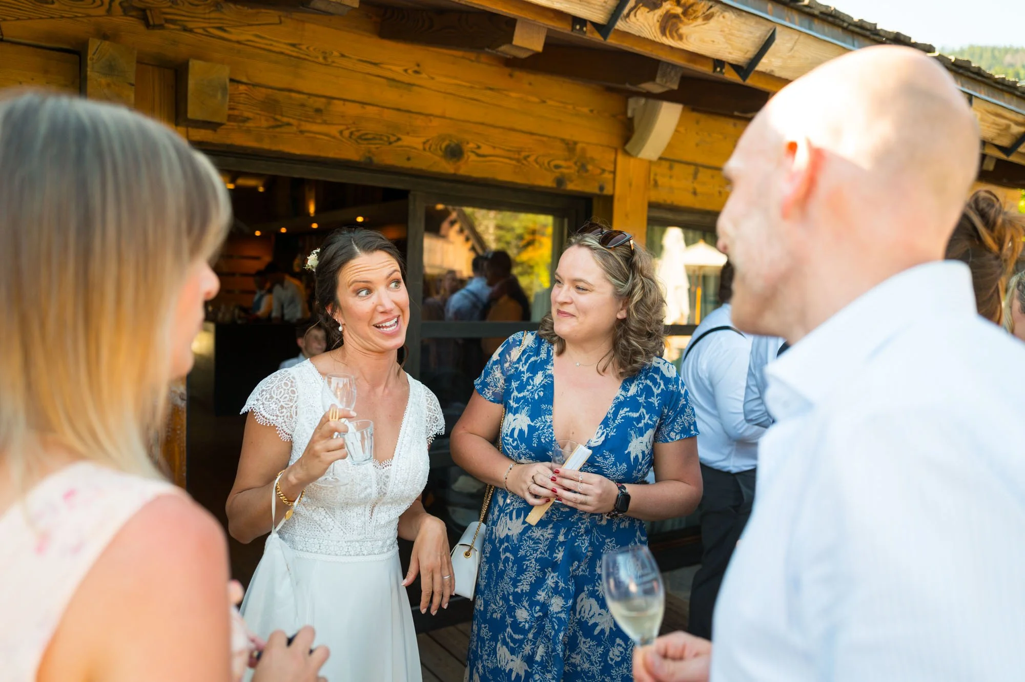 Groupe de personnes discutant lors d'une célébration en plein air, avec une femme en robe blanche au centre