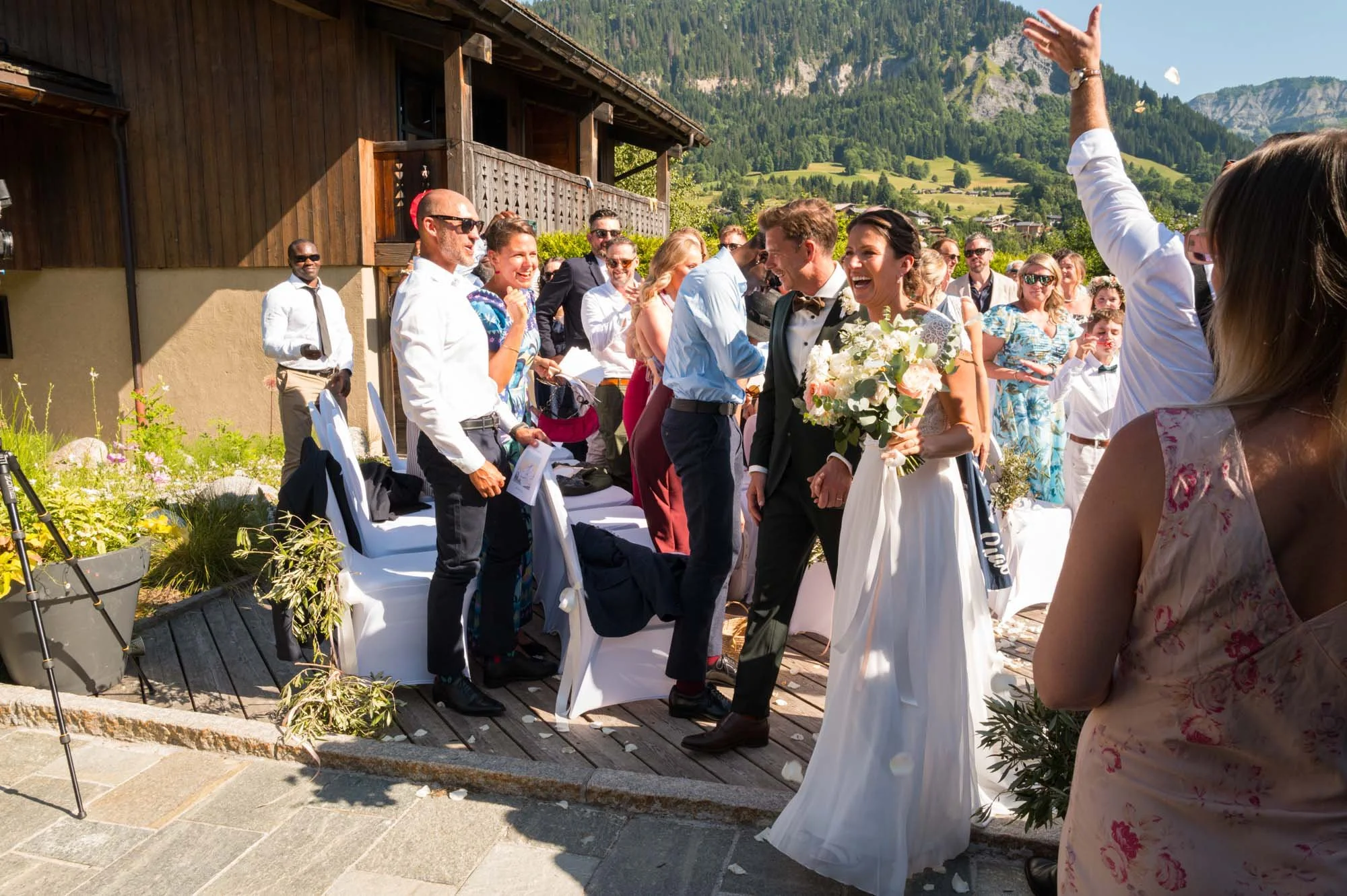 Un mariage en plein air avec le couple heureux entouré d'invités lors d'une célébration en montagne sous un ciel ensoleillé.