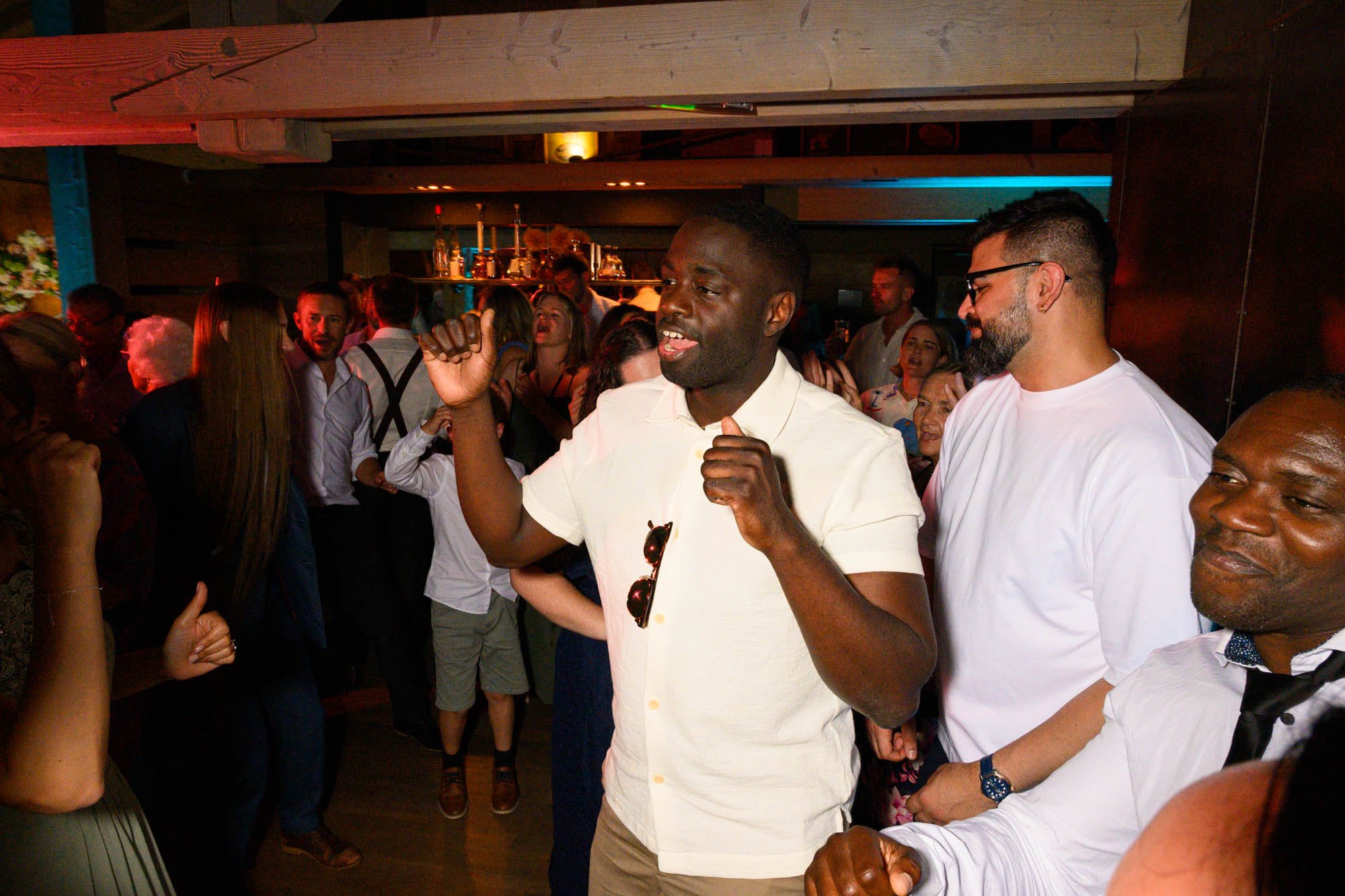Groupe de personnes dansant et socialisant lors d'une fête en intérieur, ambiance animée et conviviale.