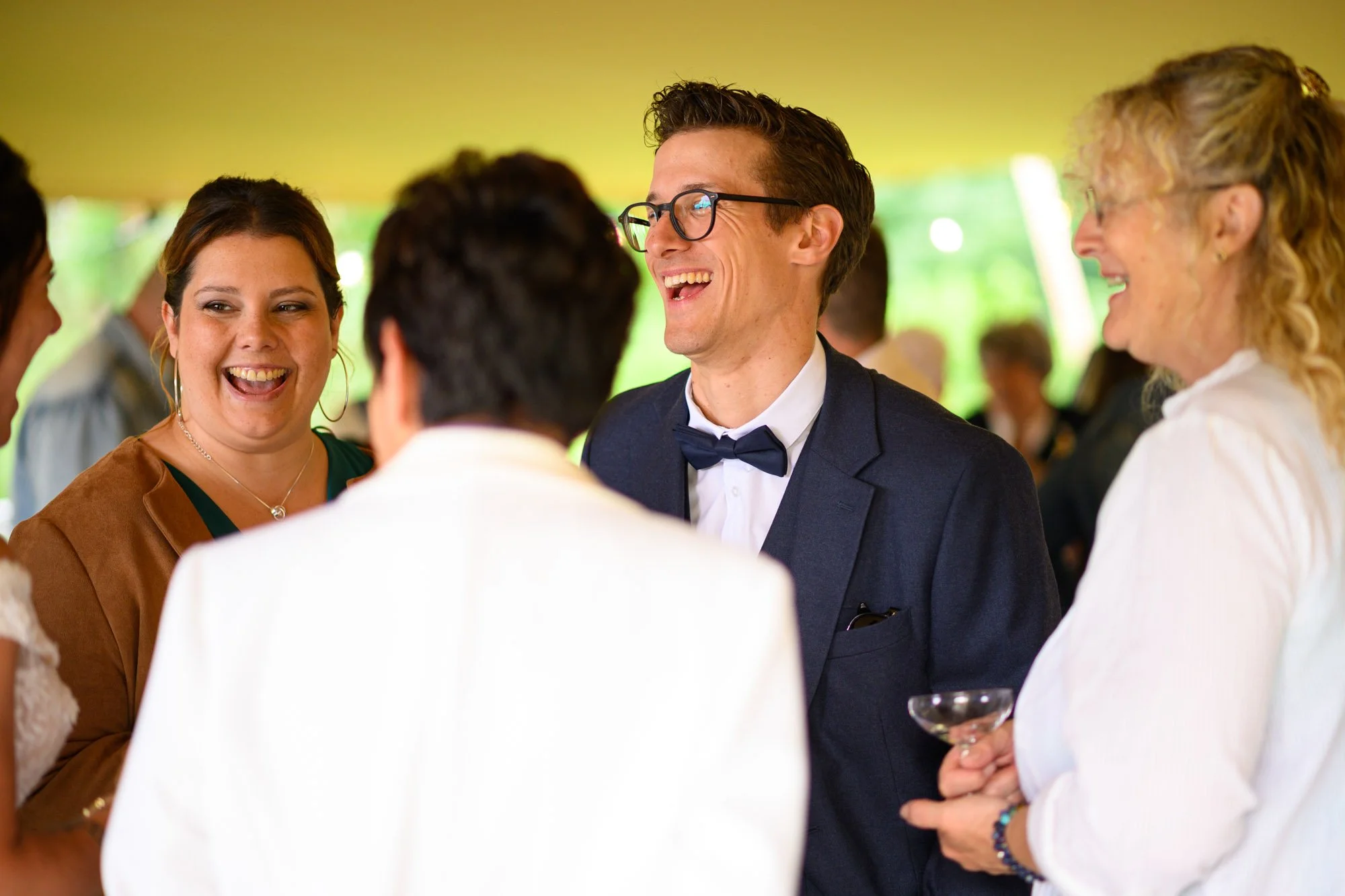 Groupe de personnes souriantes et riant lors d'une fête ou d'un rassemblement en plein air, sous un chapiteau
