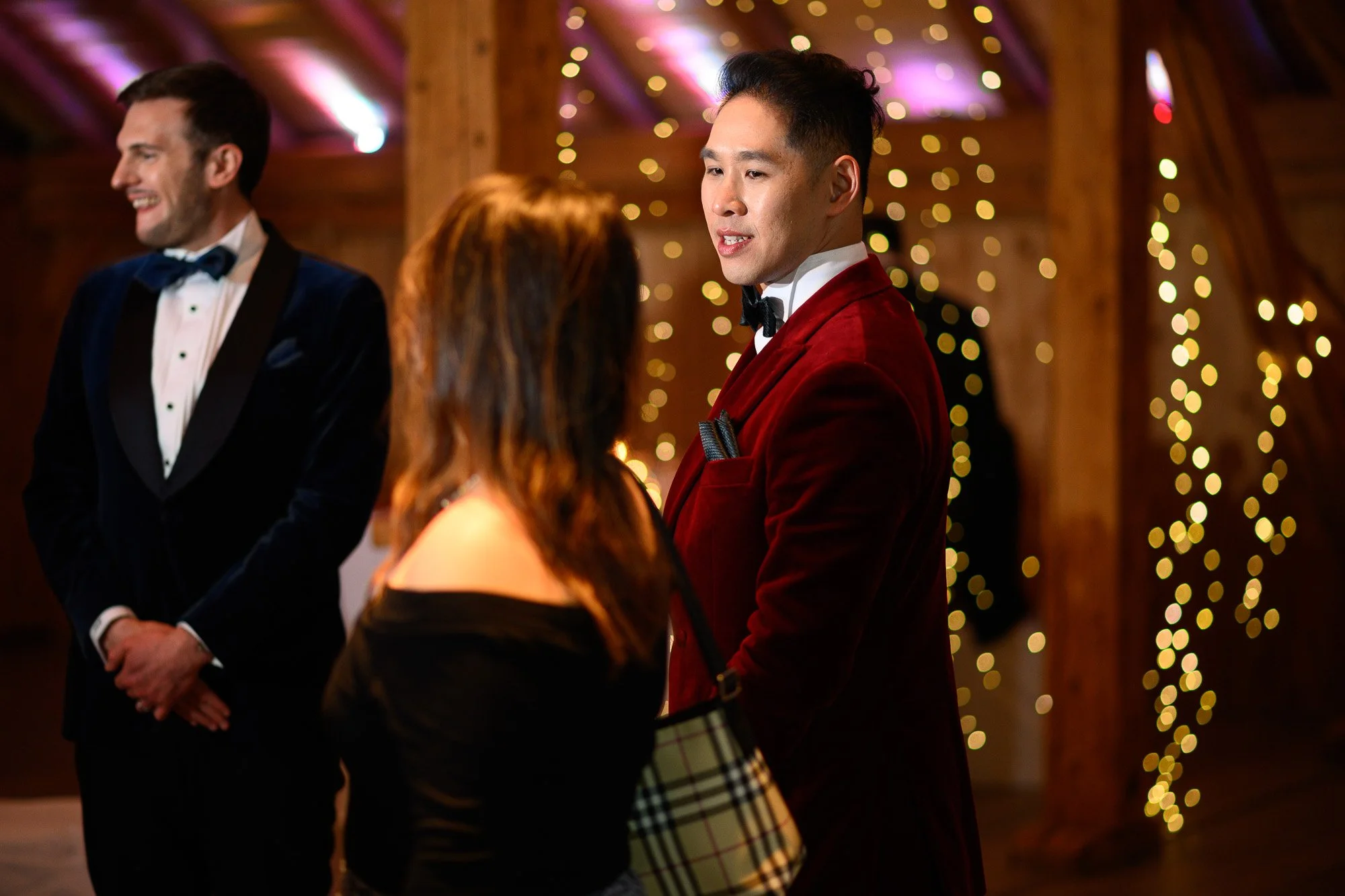 Un groupe de personnes habillées élégamment lors d'une fête ou d'un événement, avec des lumières douces en arrière-plan.