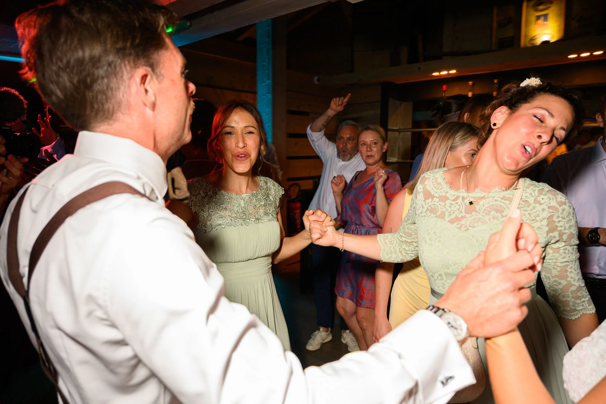 Groupe de personnes dansant et s'amusant lors d'une fête ou d'un mariage, avec des expressions joyeuses.