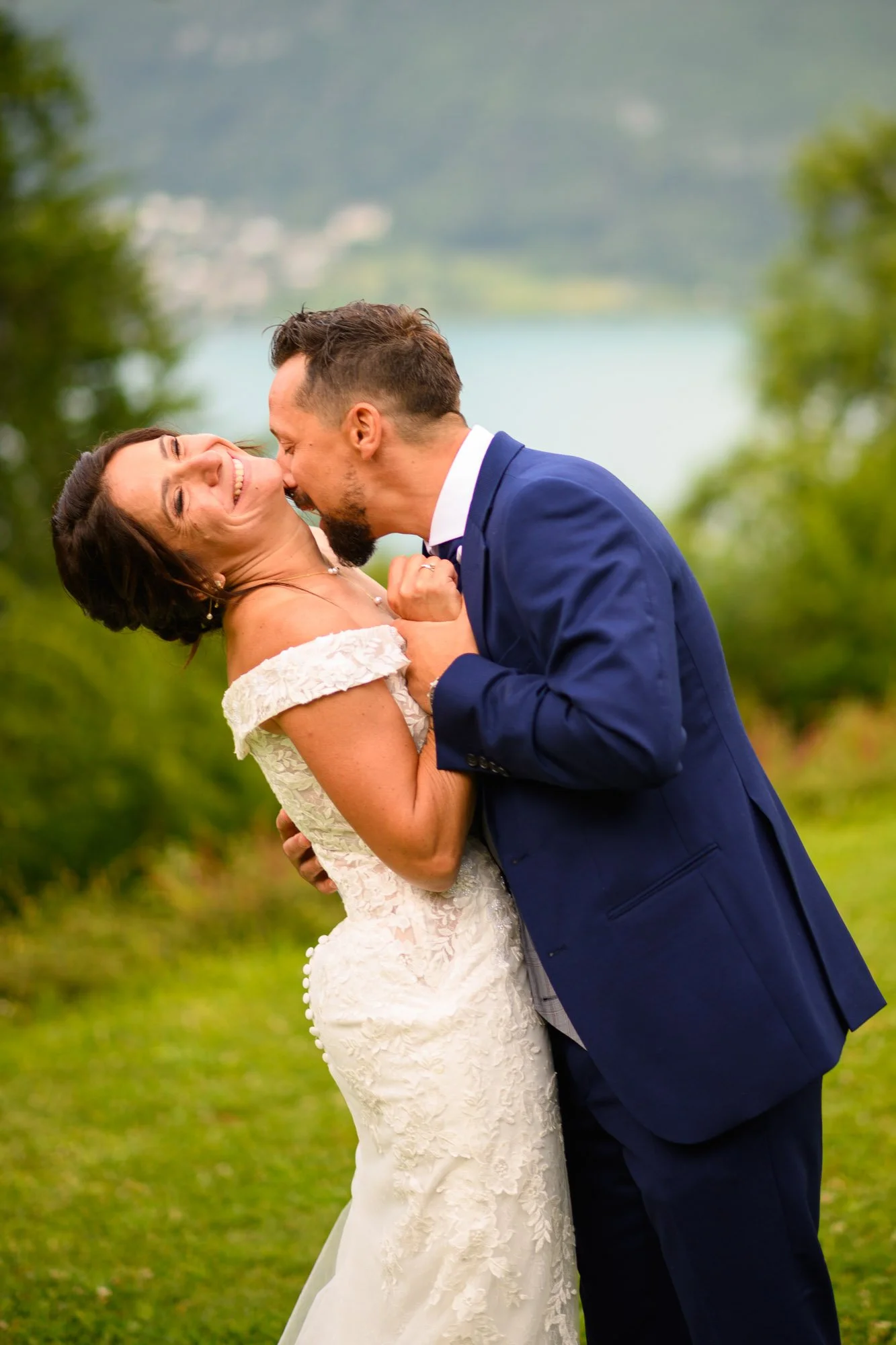 Un couple en robe de mariée et costume de mariage partage un moment de bonheur en plein air, avec un paysage naturel en arrière-plan.