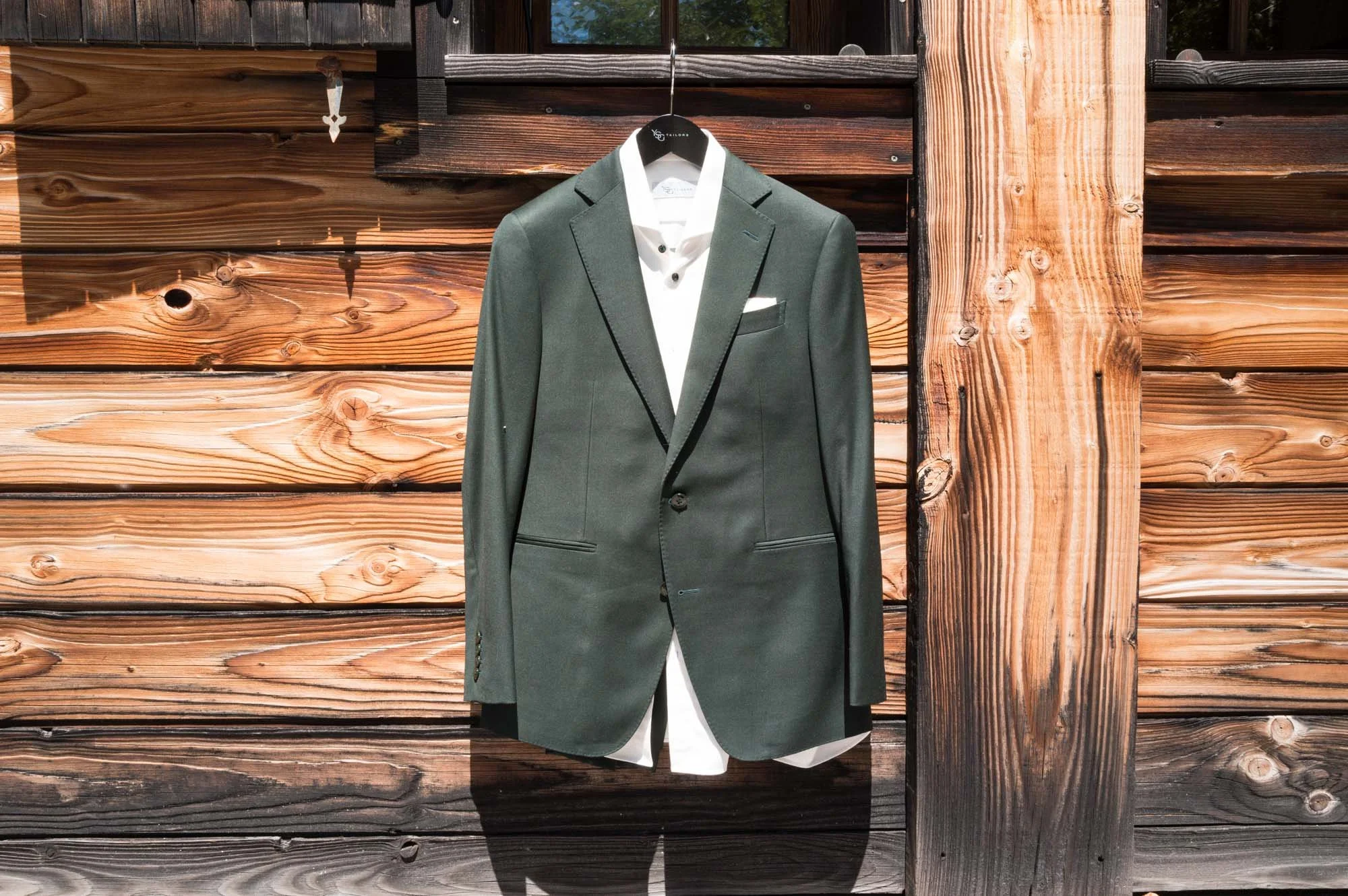 Costume de costume gris avec chemise blanche suspendu sur un support contre un mur en bois