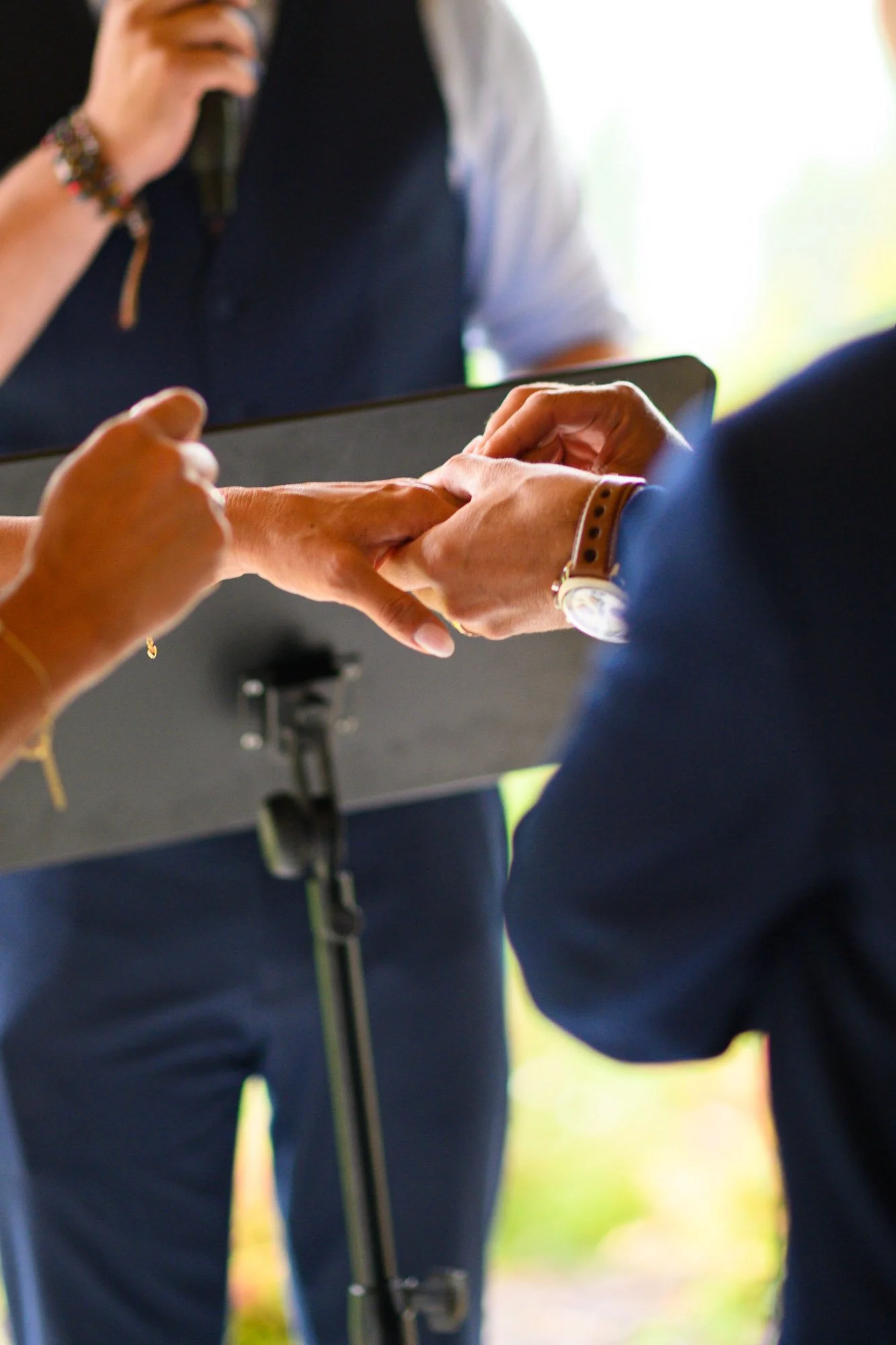 Une personne prête à échanger des alliances lors d'une cérémonie, avec une autre personne qui tient sa main.