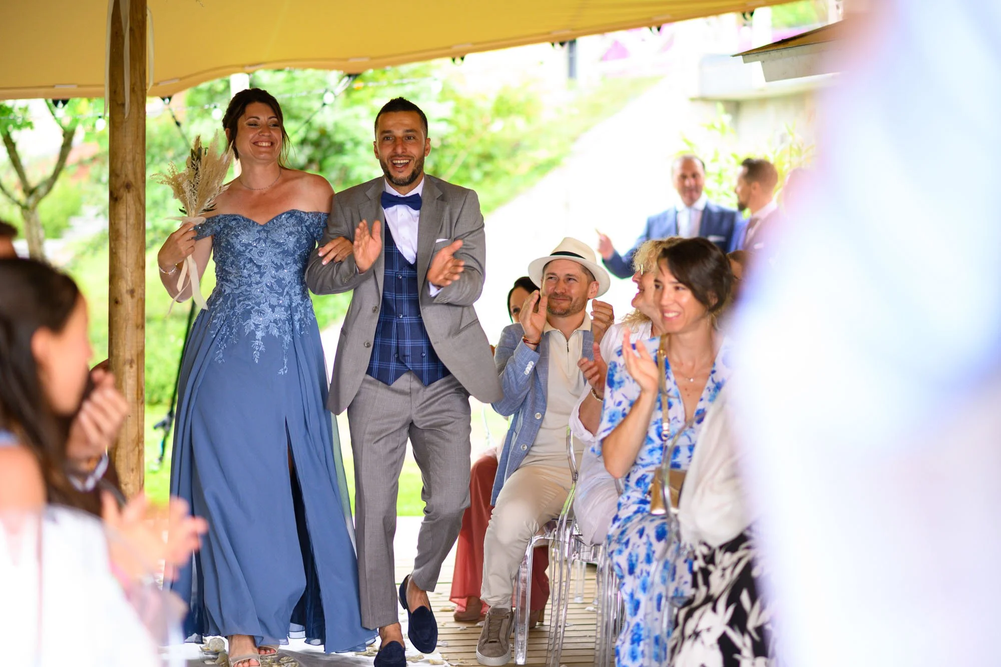 des personnes souriantes et applaudissant lors d'un mariage en extérieur sous un chapiteau