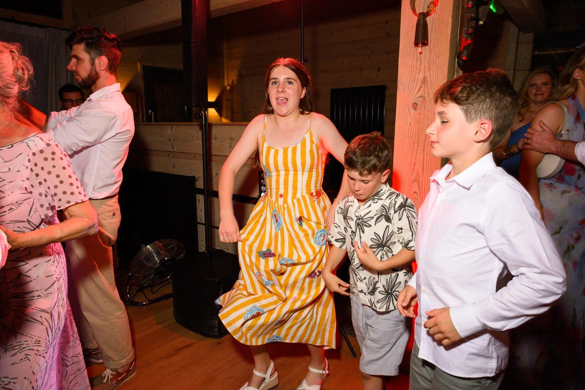 Des enfants et des adultes dansant lors d'une fête ou d'un évènement dans une ambiance chaleureuse