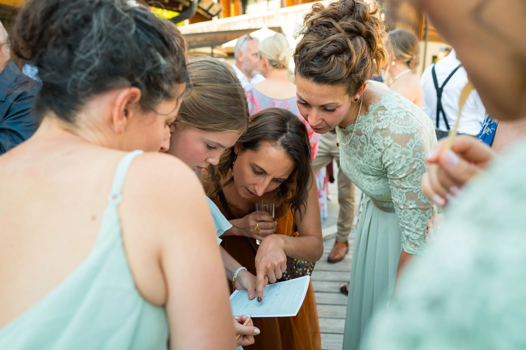 Groupe de femmes et une fille regardant un téléphone portable lors d'une réunion sociale en extérieur.
