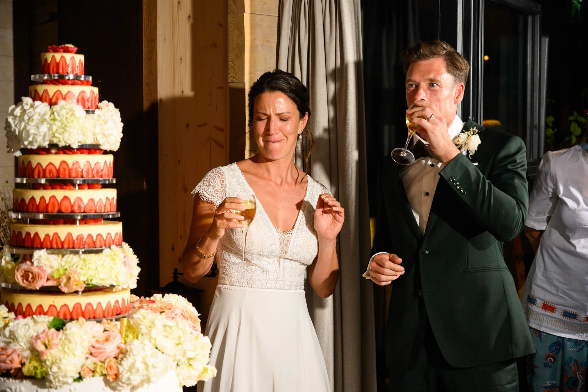 Un couple de mariés au mariage, la femme pleure en regardant le gâteau de mariage, l'homme marche en buvant du champagne, dans une salle chaude et accueillante.