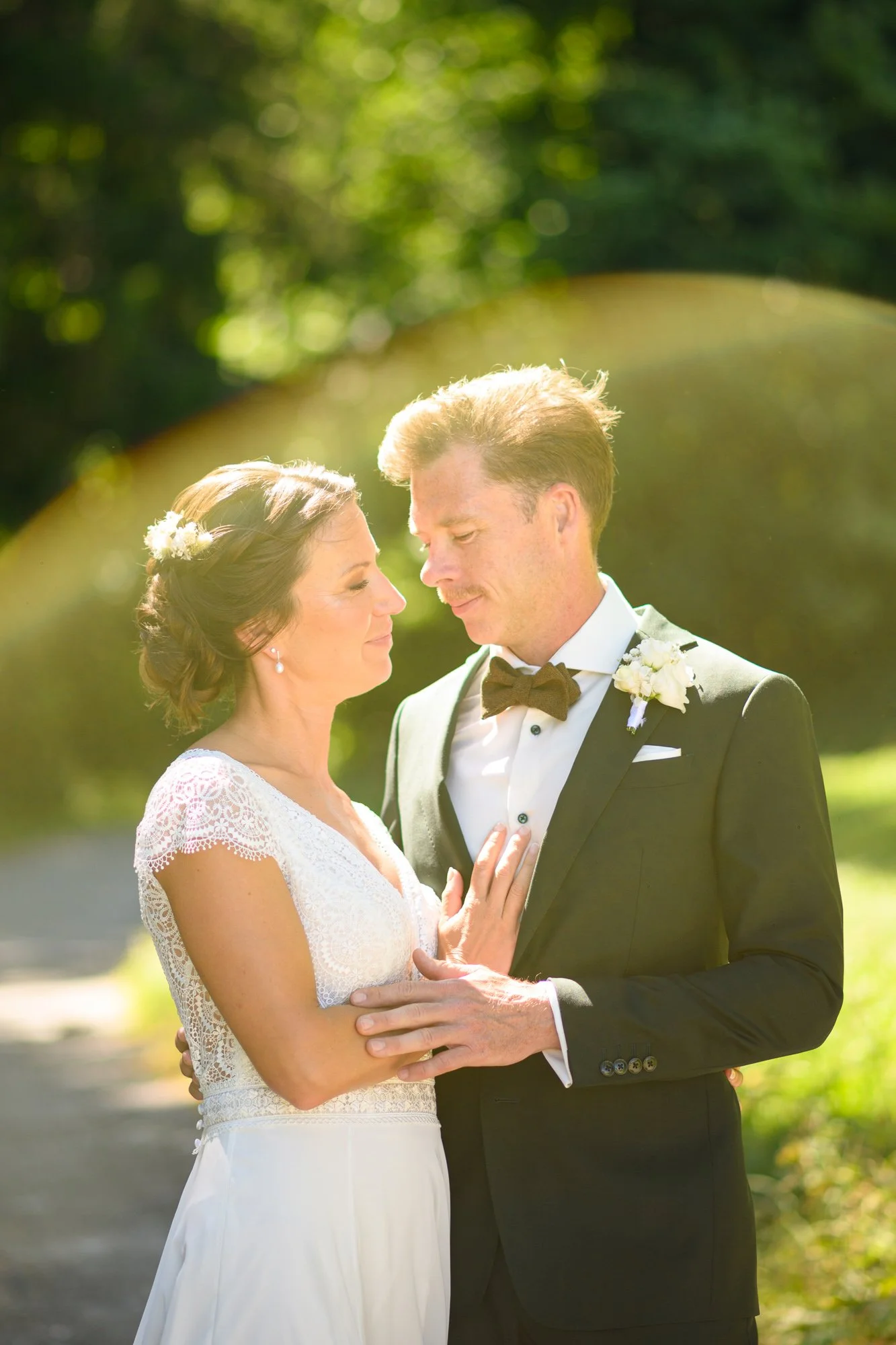 Un couple marié embrassant tendrement lors d'une séance photo en plein air, entouré de nature et de lumière naturelle.