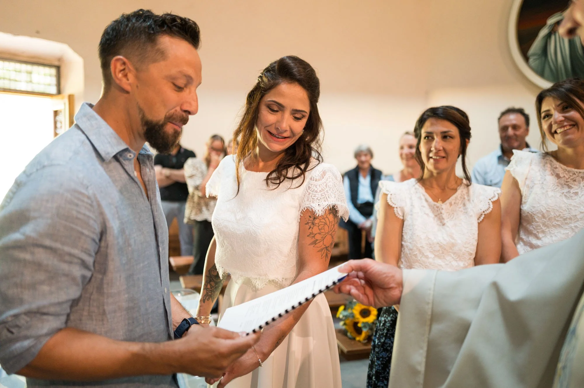 Un couple marié échange des vœux lors de leur cérémonie à l'église, entouré d'invités souriants.