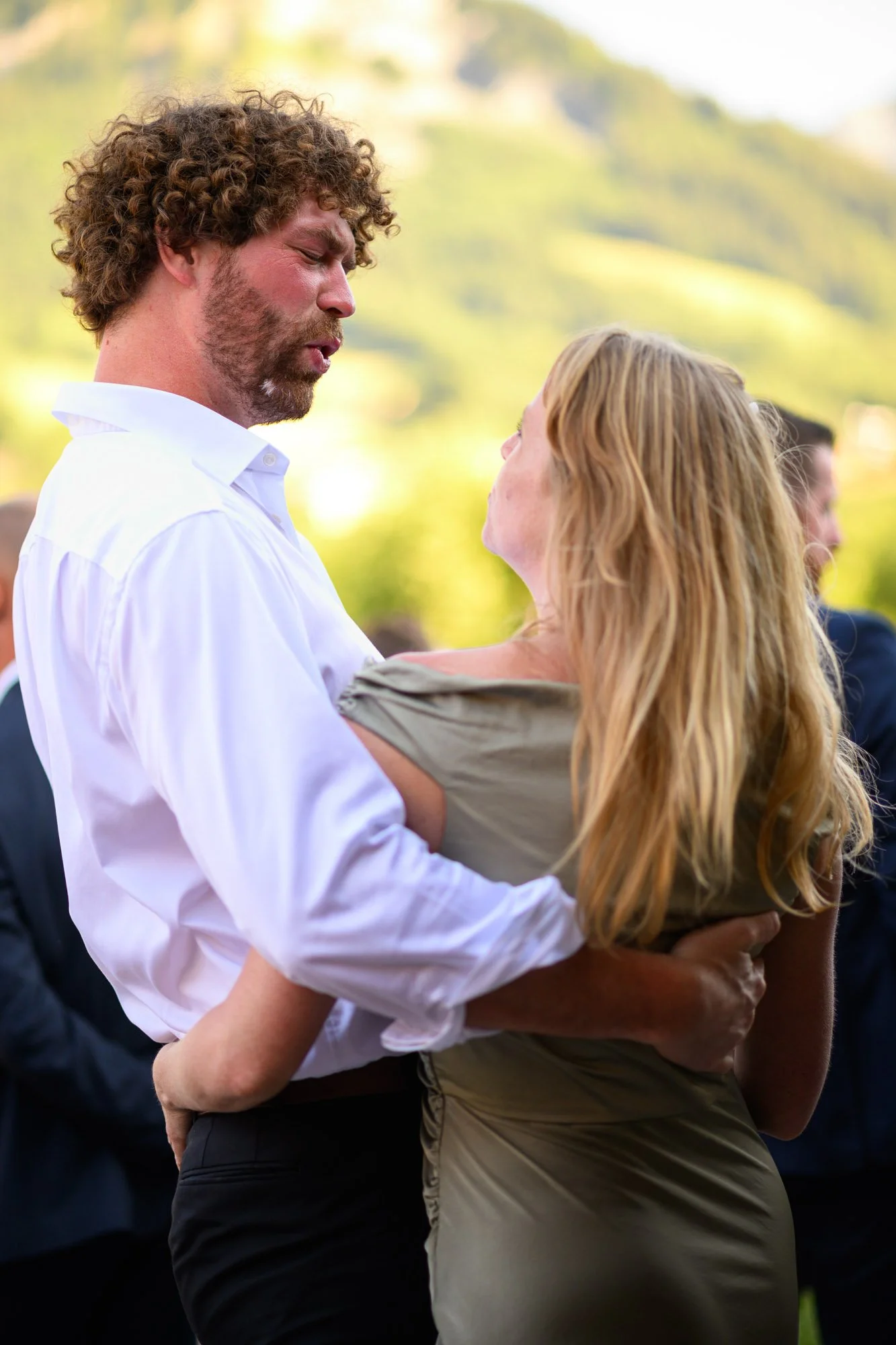 Un homme et une femme dansent lors d'une cérémonie en plein air, avec un fond de nature verdoyante.