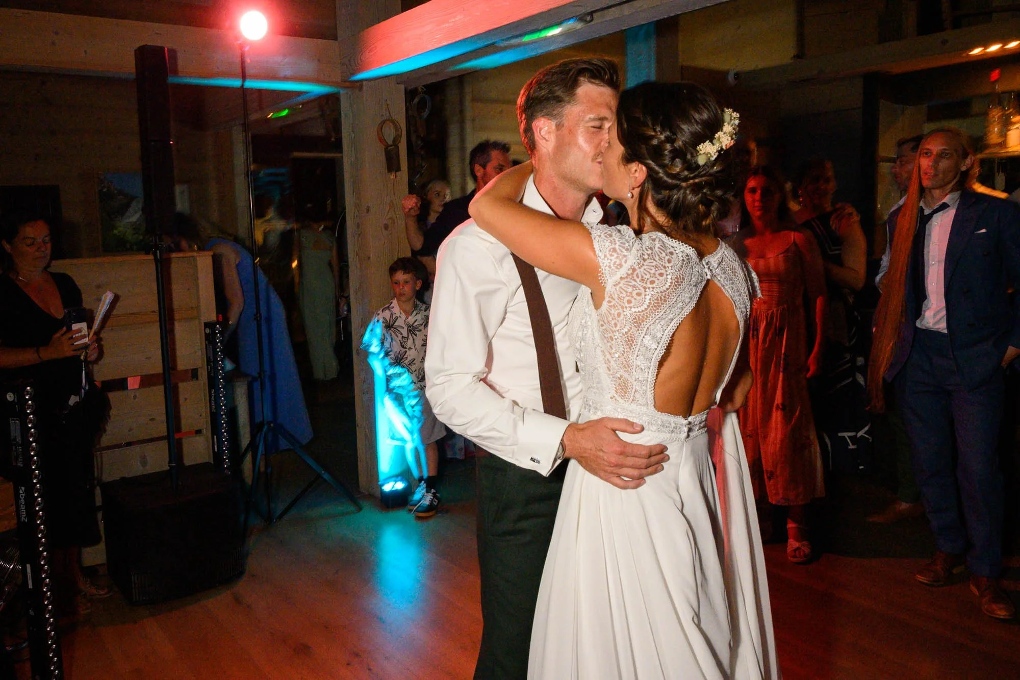 Un couple de mariés danse lors de leur mariage, entourés d'invités dans une ambiance chaleureuse.
