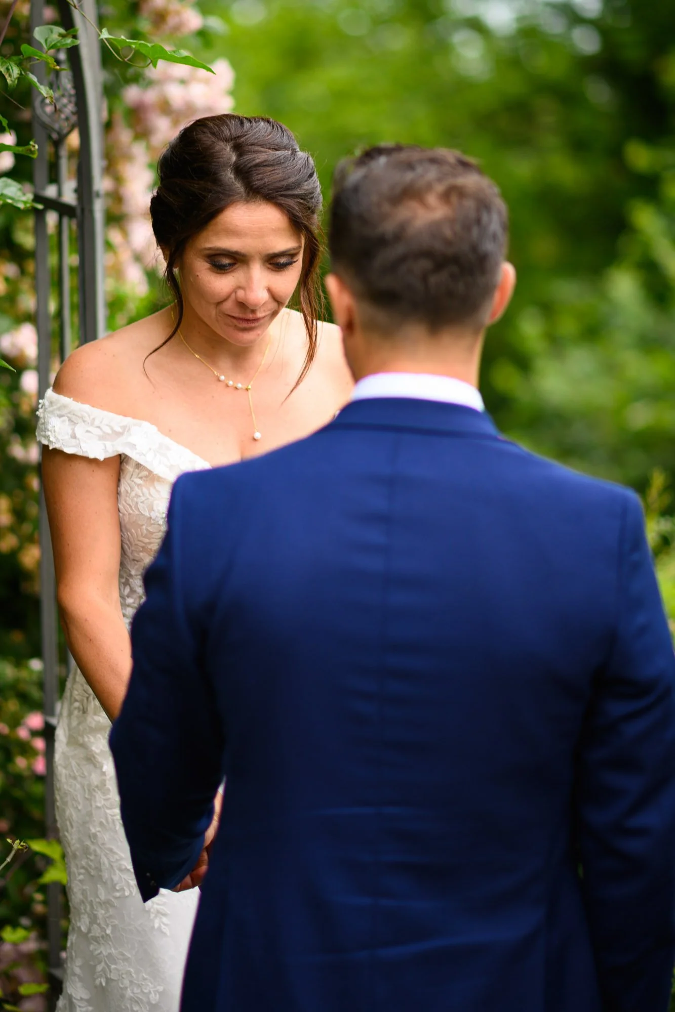 Un couple en robe et costume se tenant la main lors d'un mariage en plein air au milieu de la verdure.