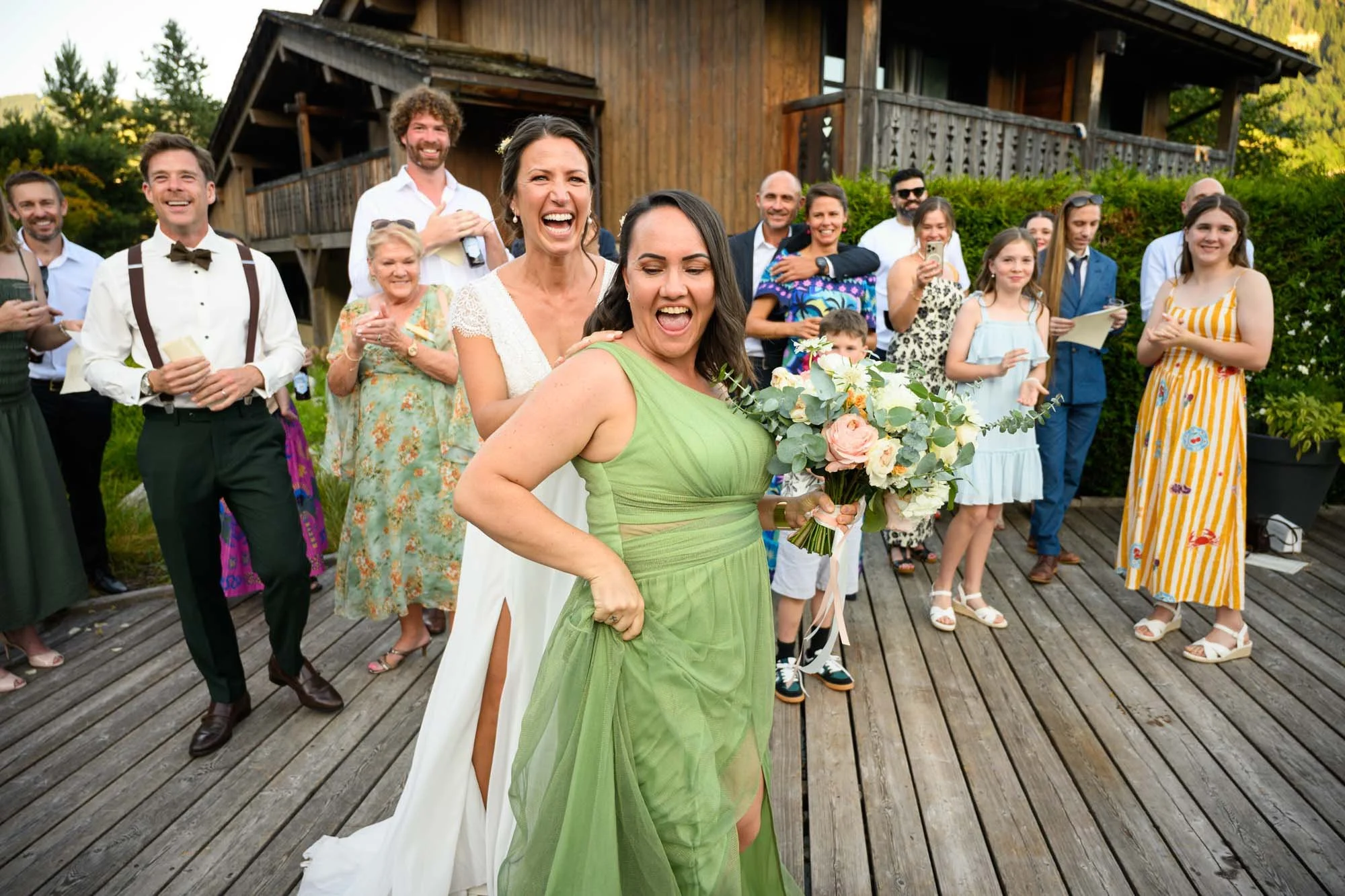 Animation d'un mariage avec une mariée et une invitée en robe verte qui sourient, entourées d'amis et famille lors d'une célébration en plein air