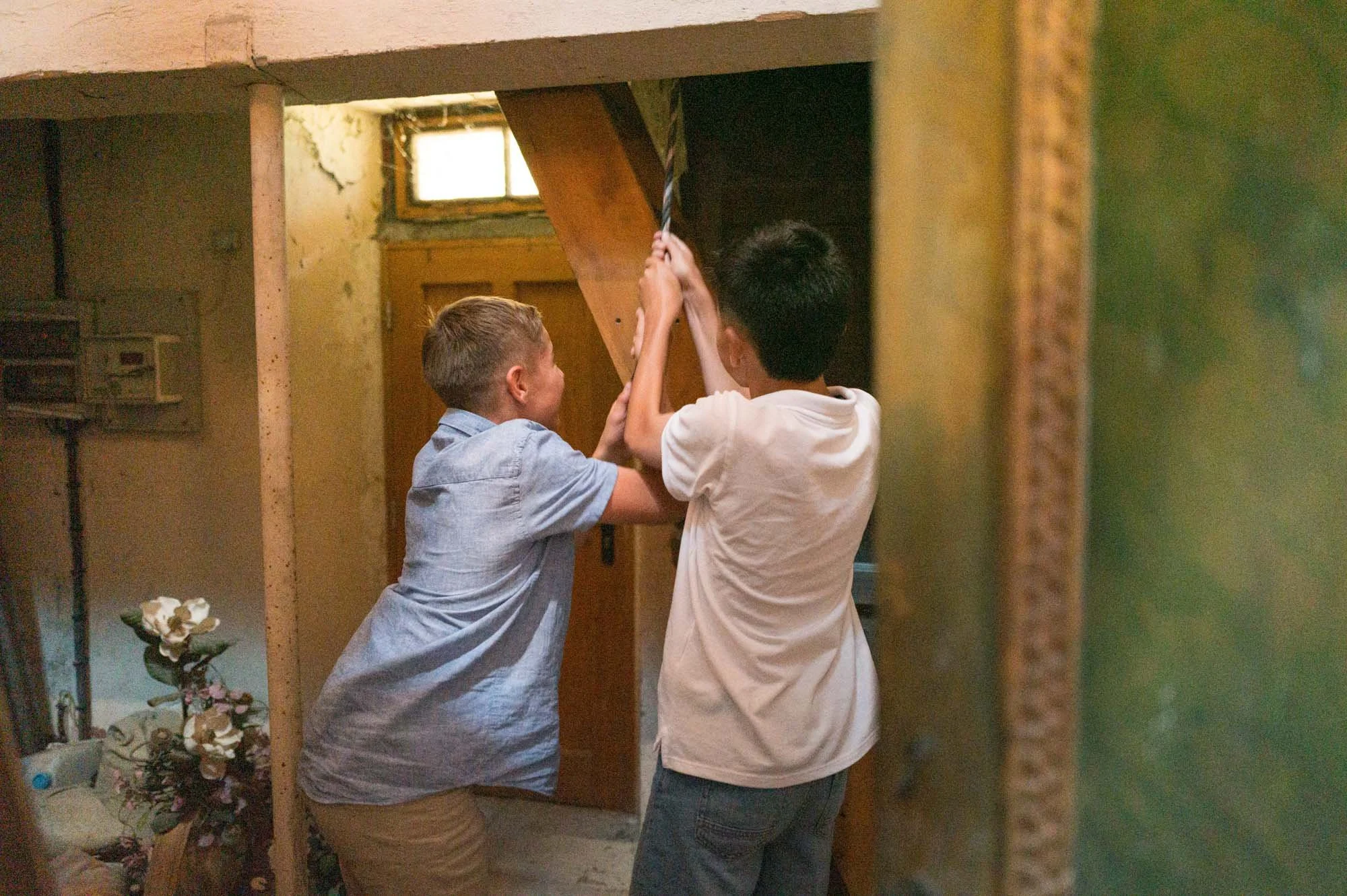 Deux garçons jouent à leur jeu dans une petite pièce en bois, l'un tenant une corde.