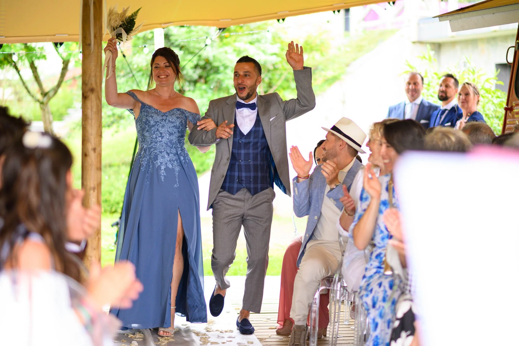 Un mariage en plein air avec la mariée et le marié qui entrent en dansant, entourés d'invités joyeux.
