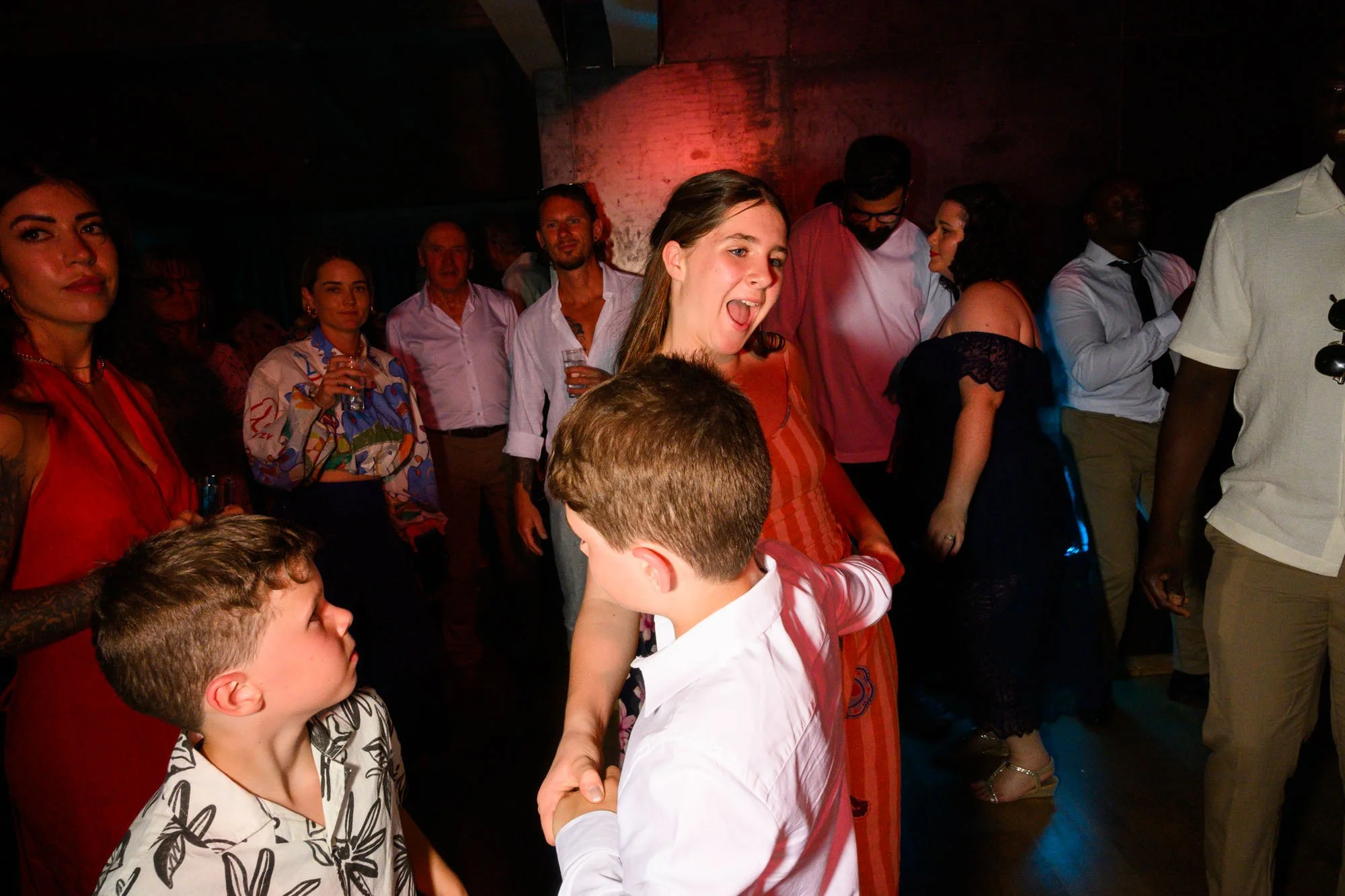 Groupe de personnes dansant et socialisant, ambiance festive, éclairage tamisé.